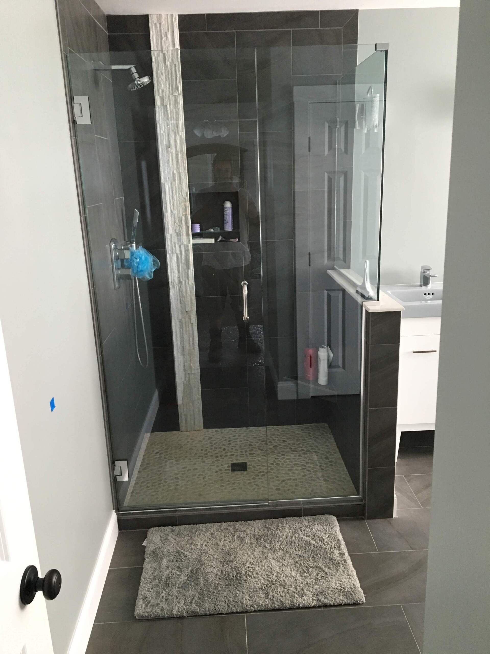 A bathroom with a walk in shower and a rug on the floor.