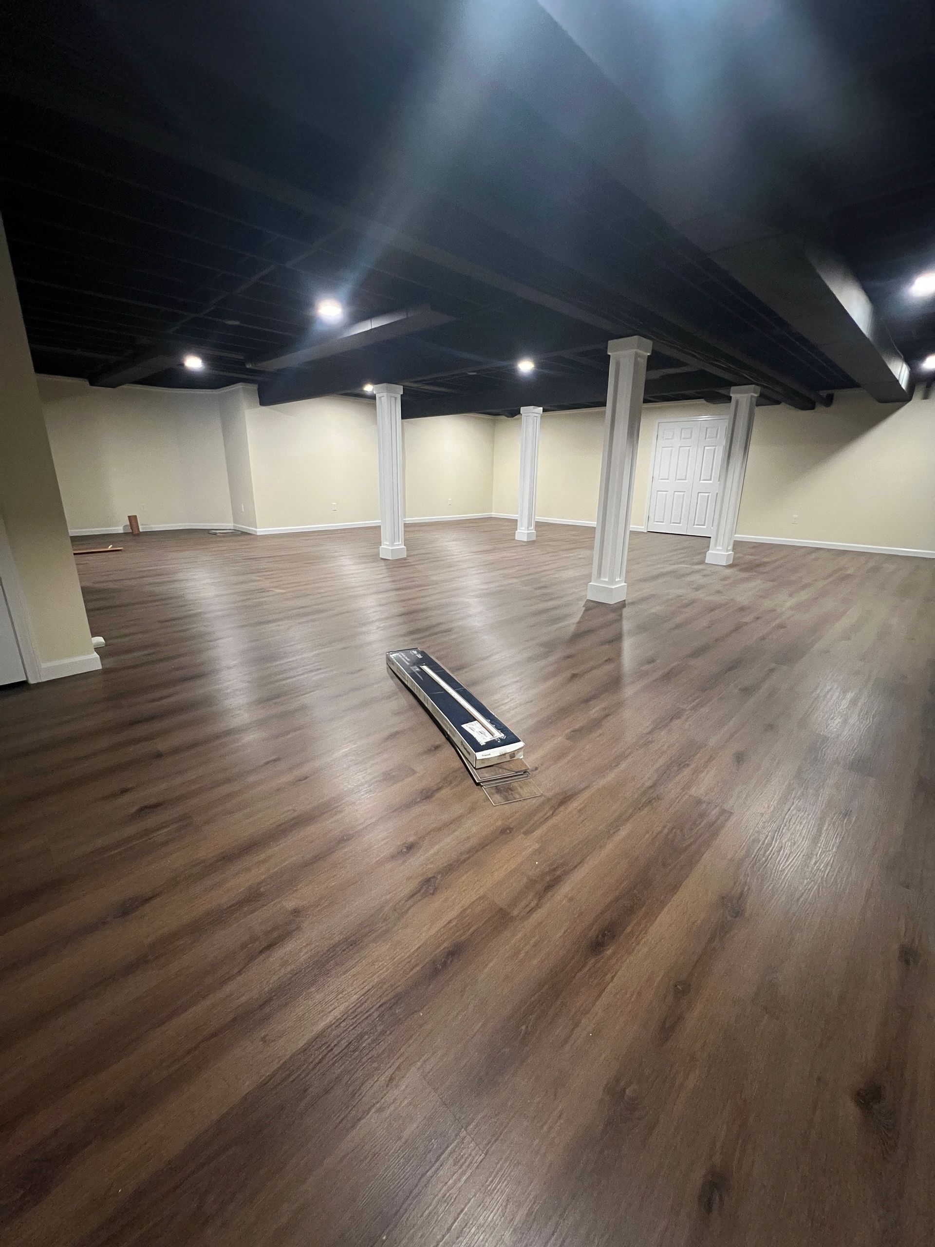 A large empty room with wooden floors and columns.