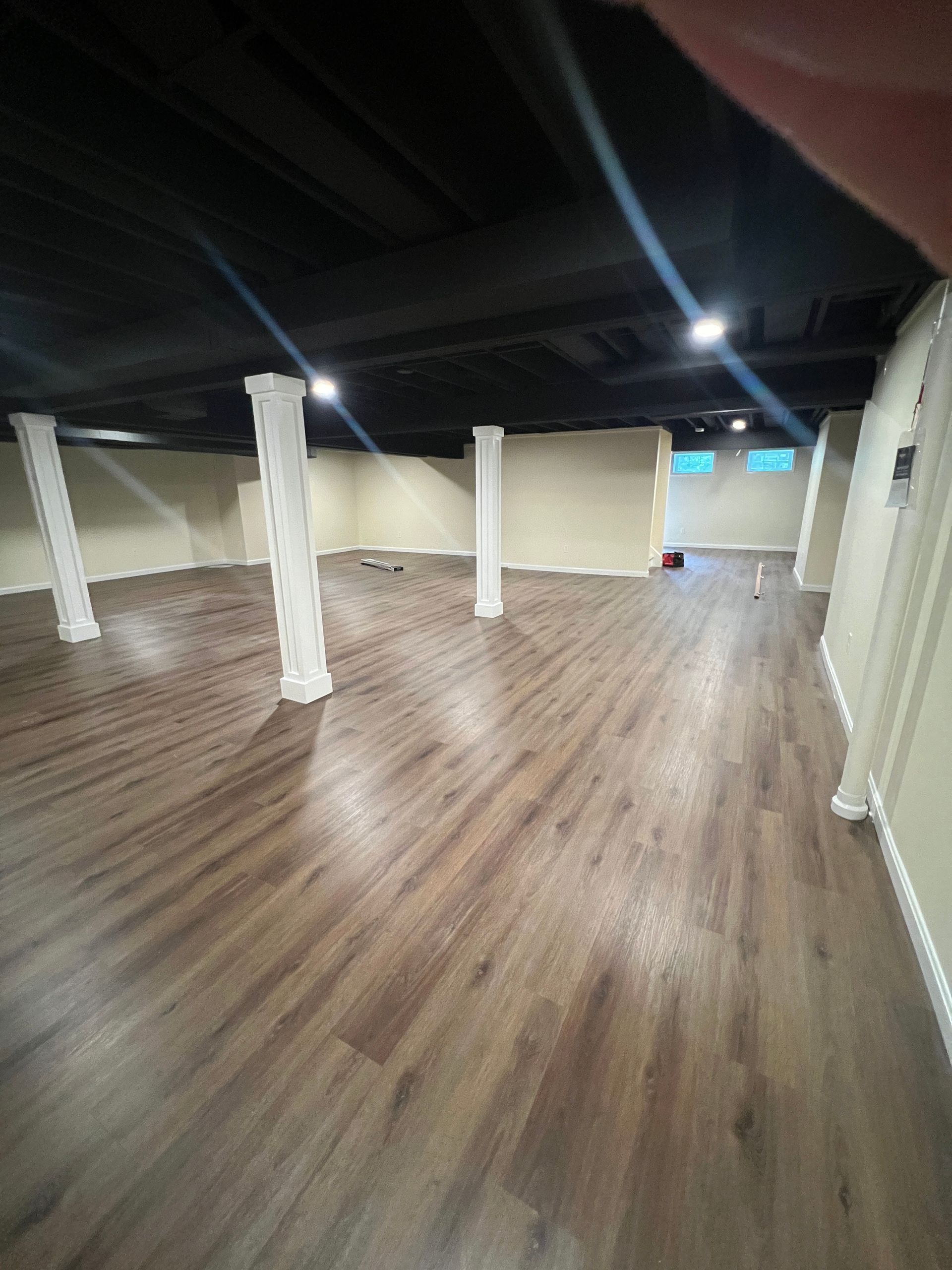 Cozy family room in a basement with corner sofa and brown rug.