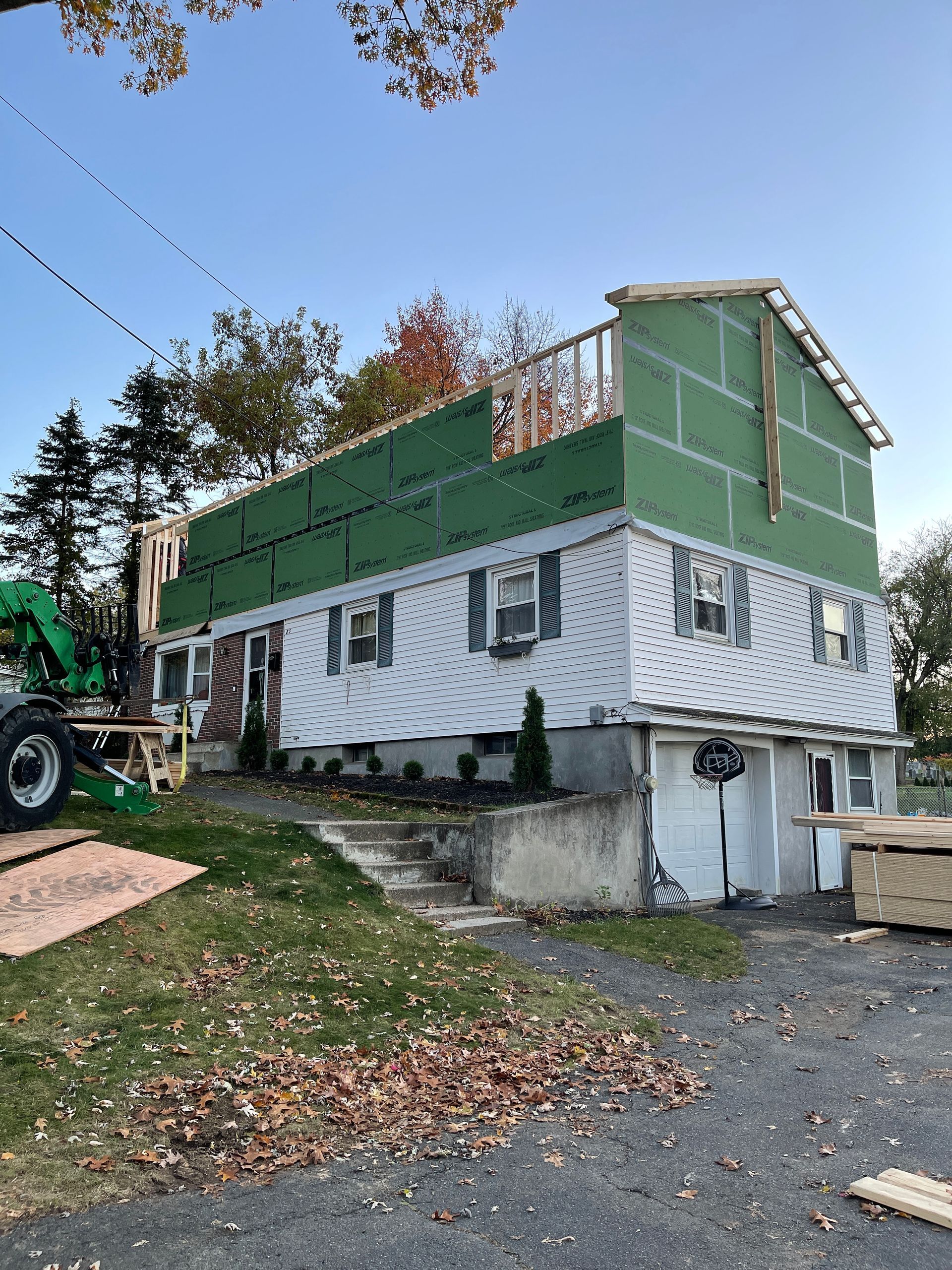 A house is being built with a green tractor in front of it.