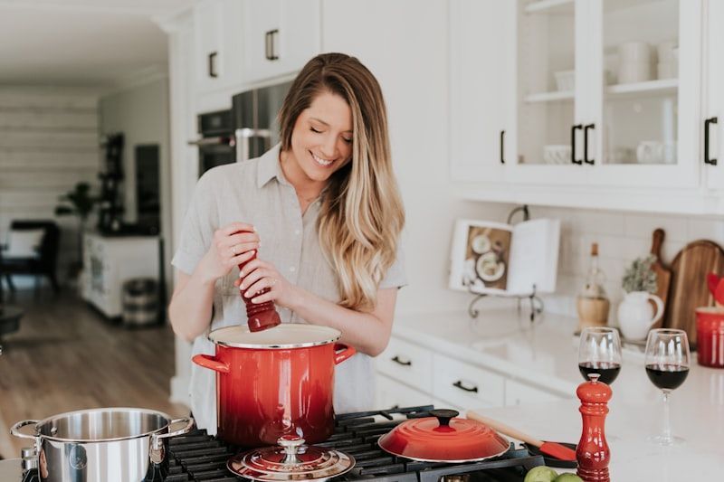 Woman cooking in a bright kitchen, stirring a red pot on the stove.