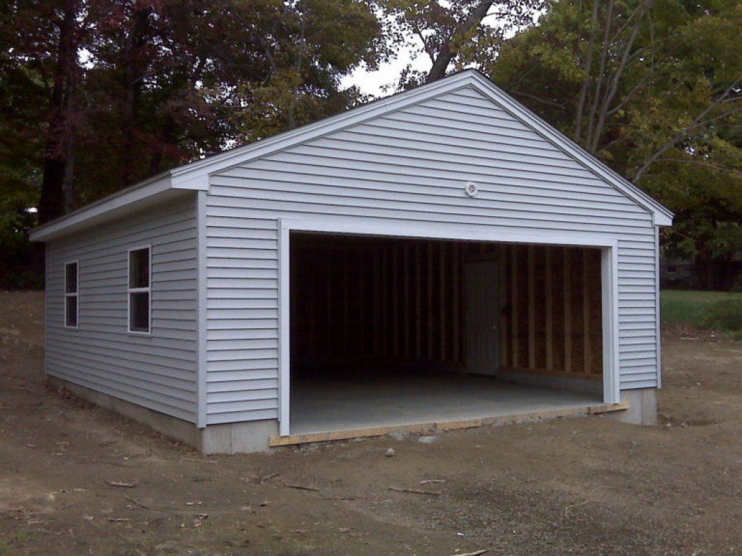 A white garage with the door open and trees in the background