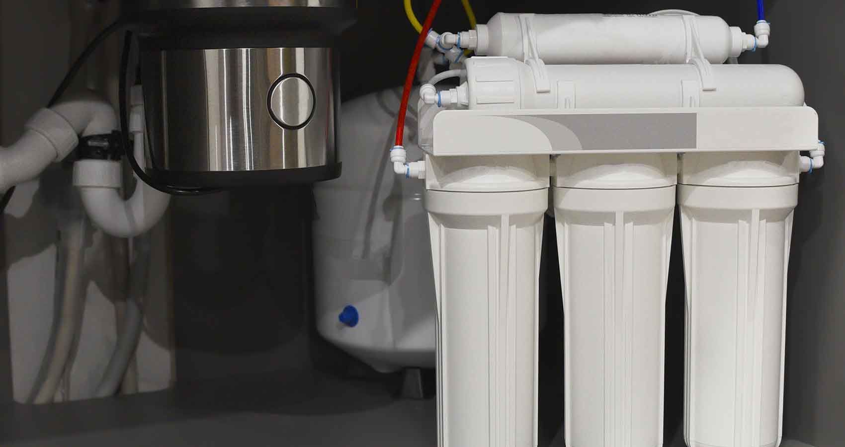 A water filter is sitting under a sink in a kitchen.