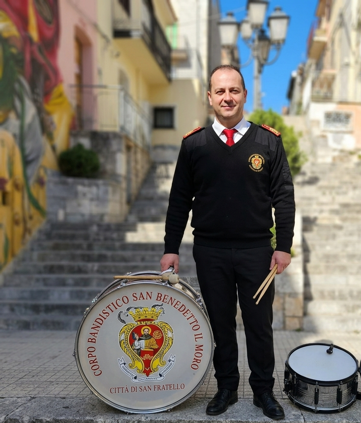 Giacca in stile militare gialla e rossa con ricami floreali di perline, spalline bianche con frange e fascia verde decorata con perline.