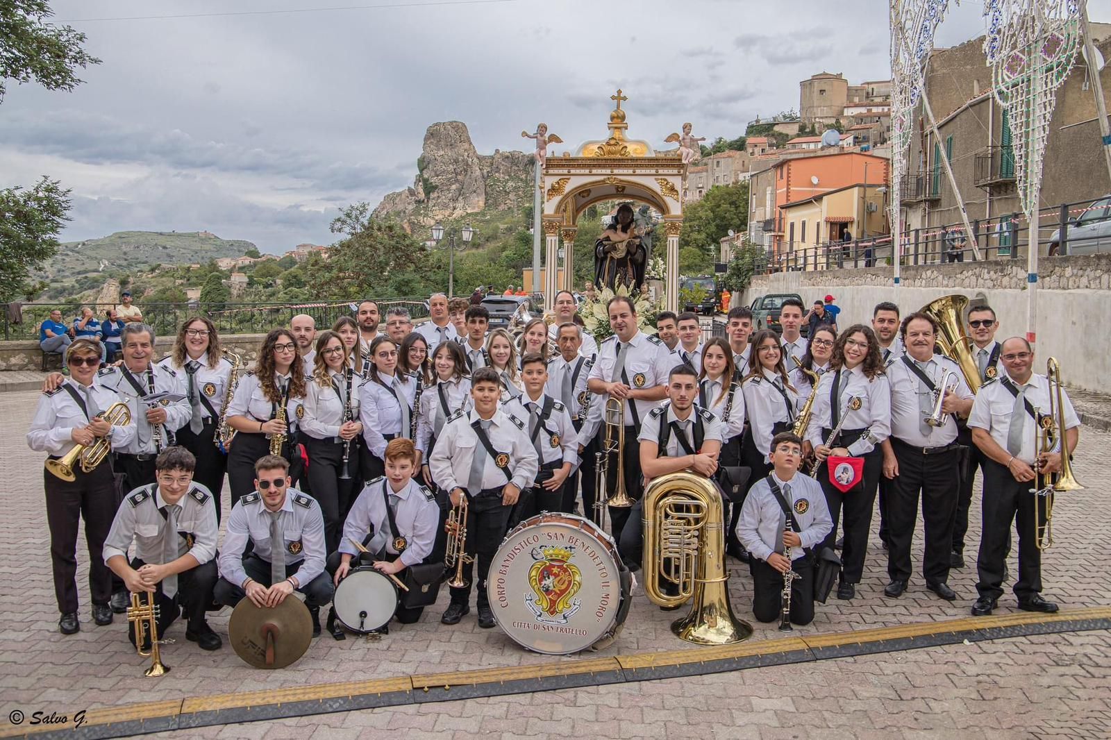 Giacca in stile militare gialla e rossa con ricami floreali di perline, spalline bianche con frange e fascia verde decorata con perline.
