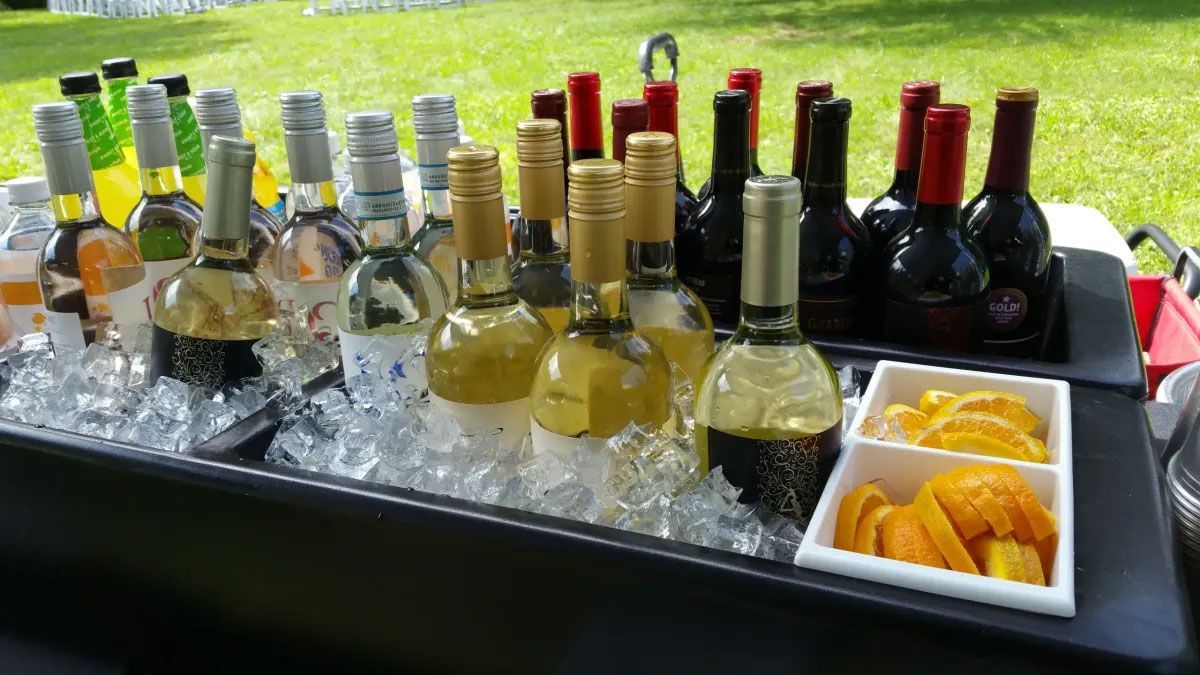 A cooler filled with ice and bottles of wine.