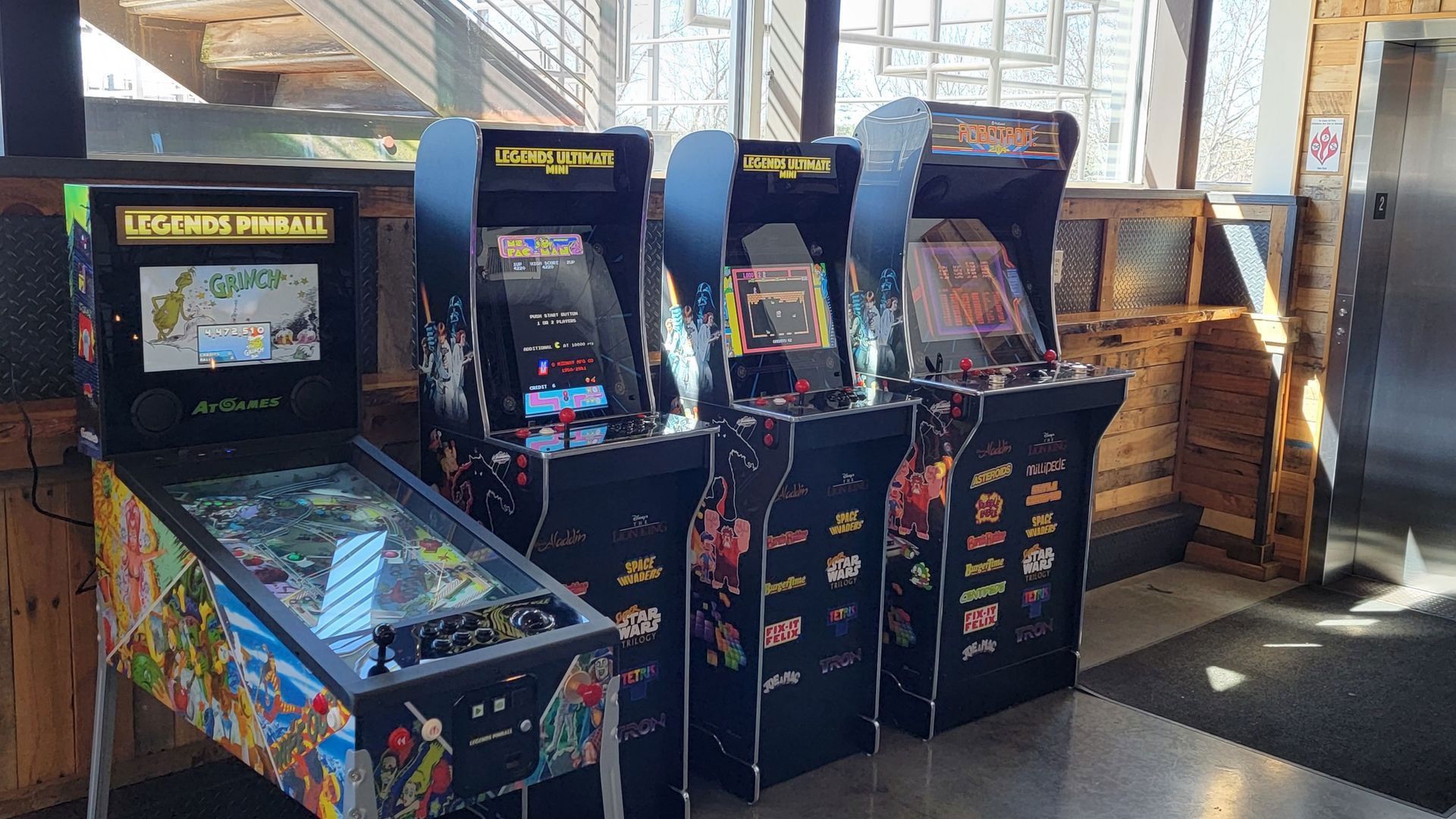 A row of pinball machines are lined up in a room.
