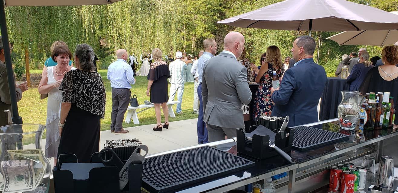 A group of people are standing around a bar at a wedding reception.