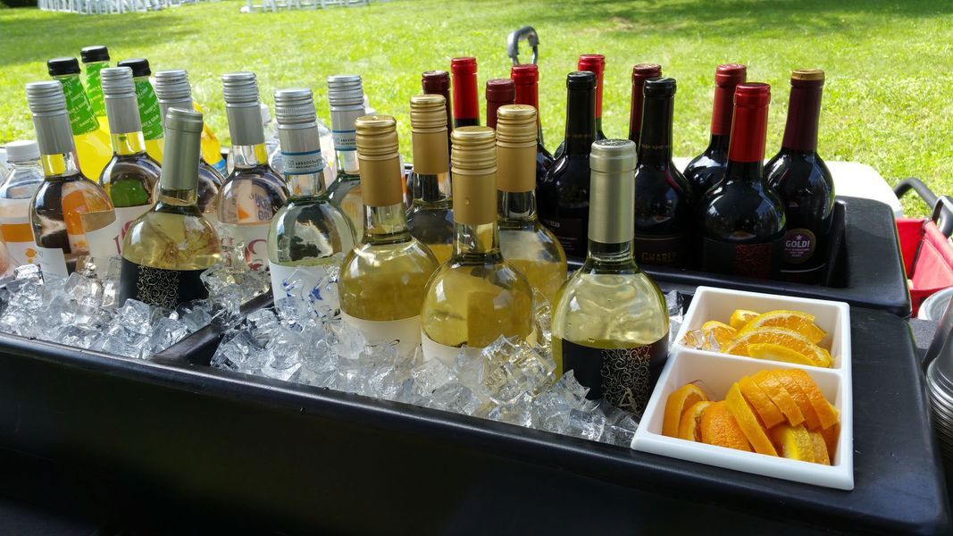 A cooler filled with ice and bottles of wine and fruit.