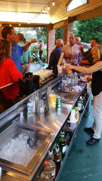 A group of people are standing around a bar.
