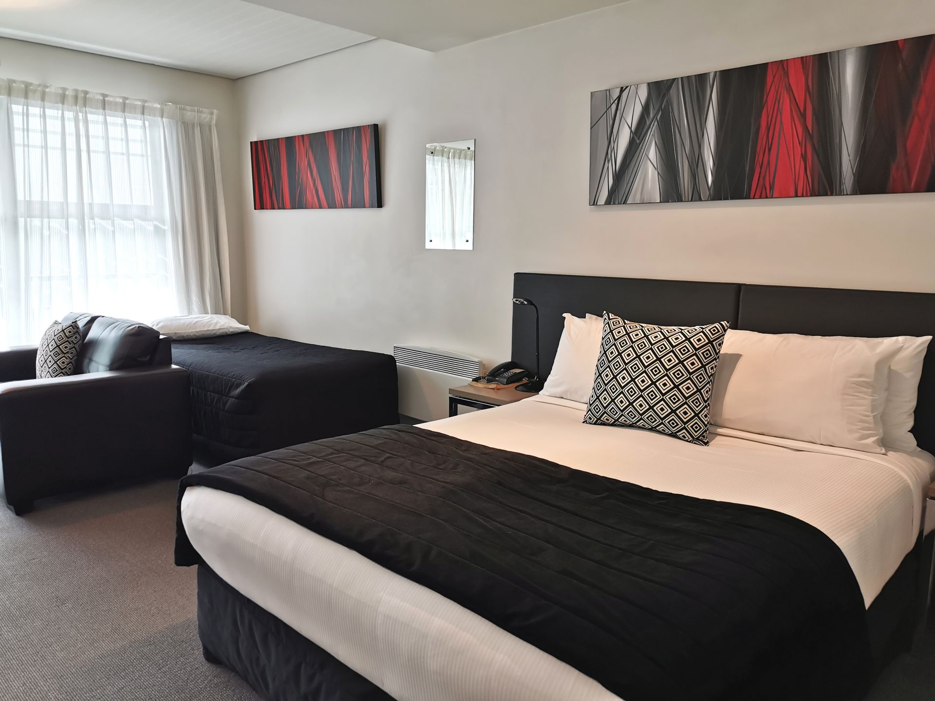 A hotel room with a bed and three paintings on the wall