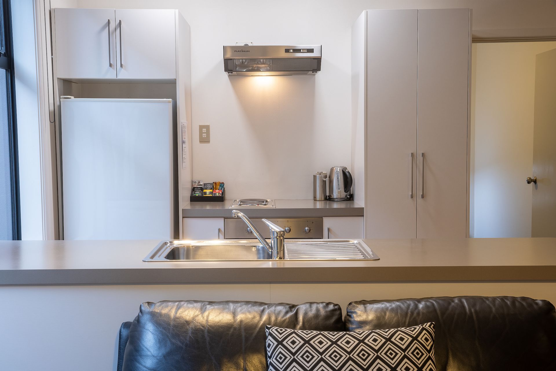 A kitchen with a sink and a couch in the foreground