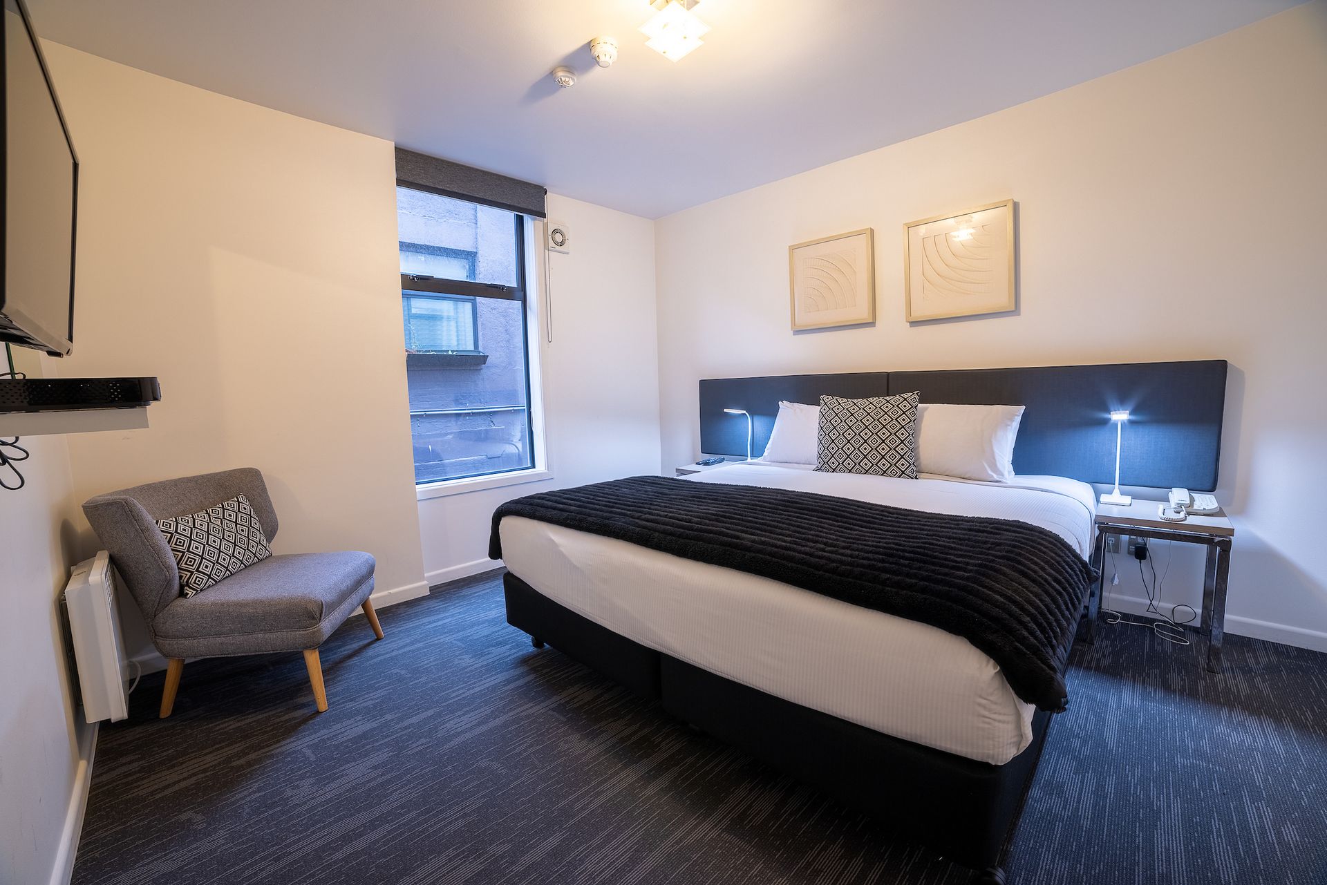 A hotel room with a large bed , chair and television.