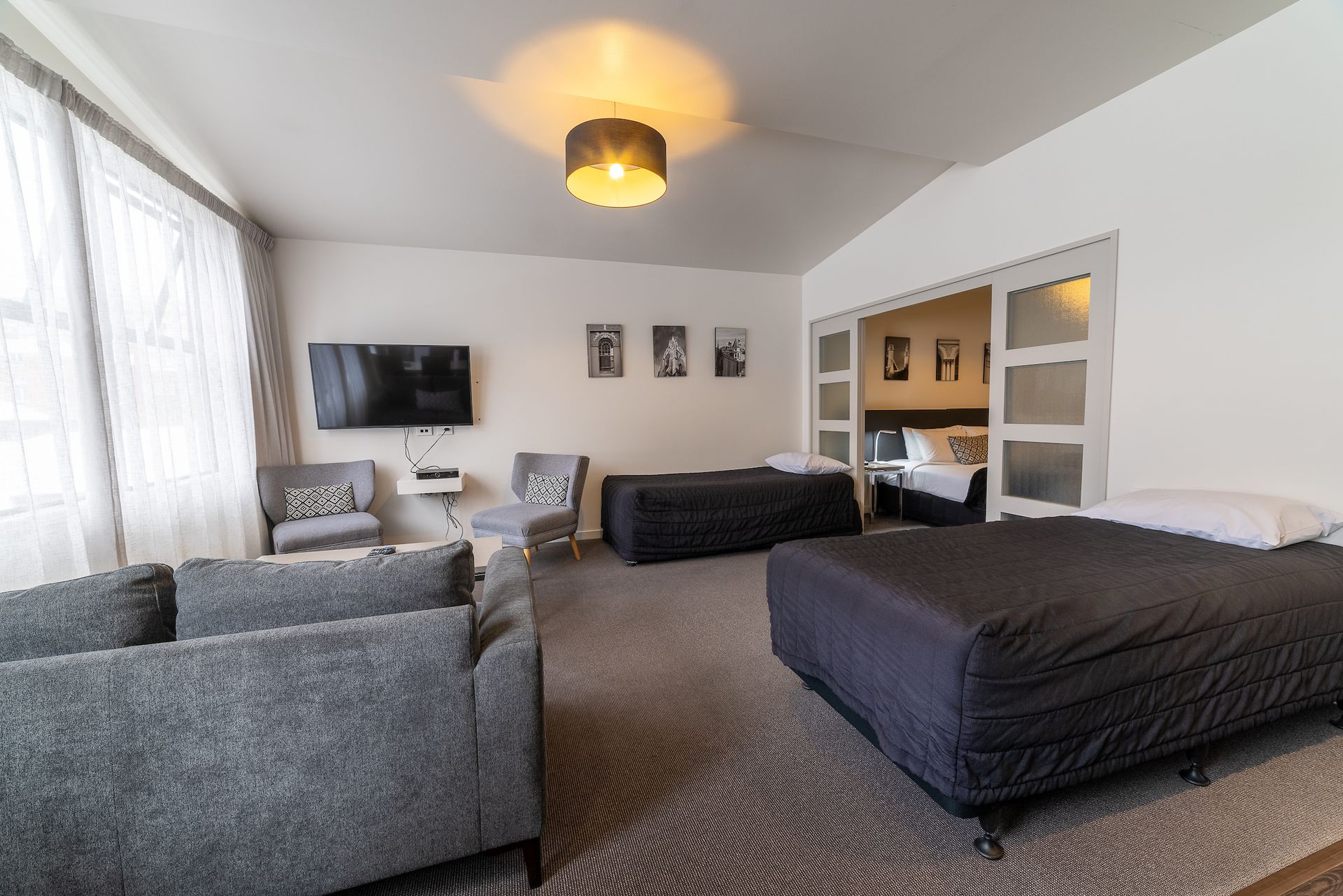 A living room with a couch , chairs , a bed and a flat screen tv.