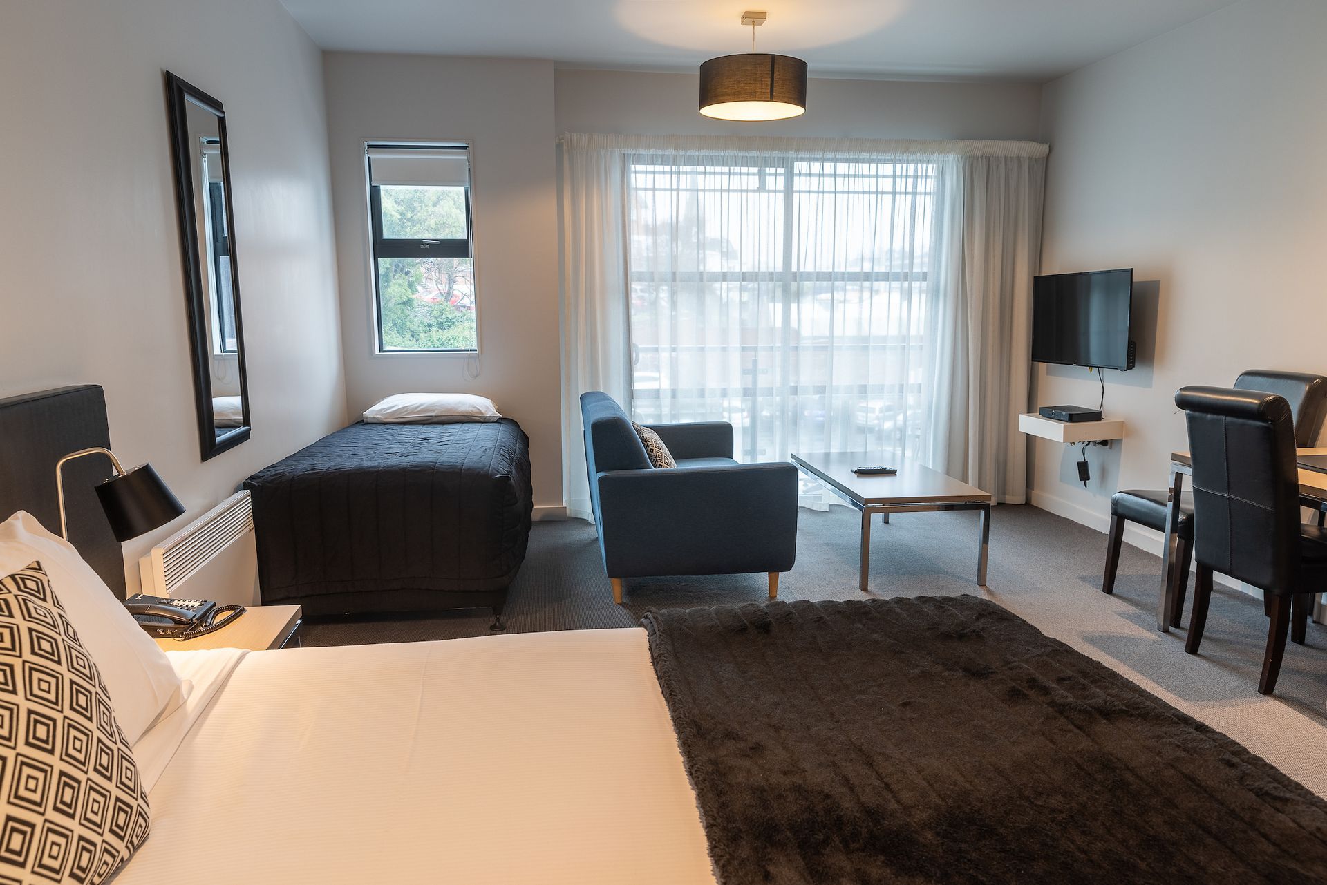 A hotel room with two beds , a couch , a desk and a television.