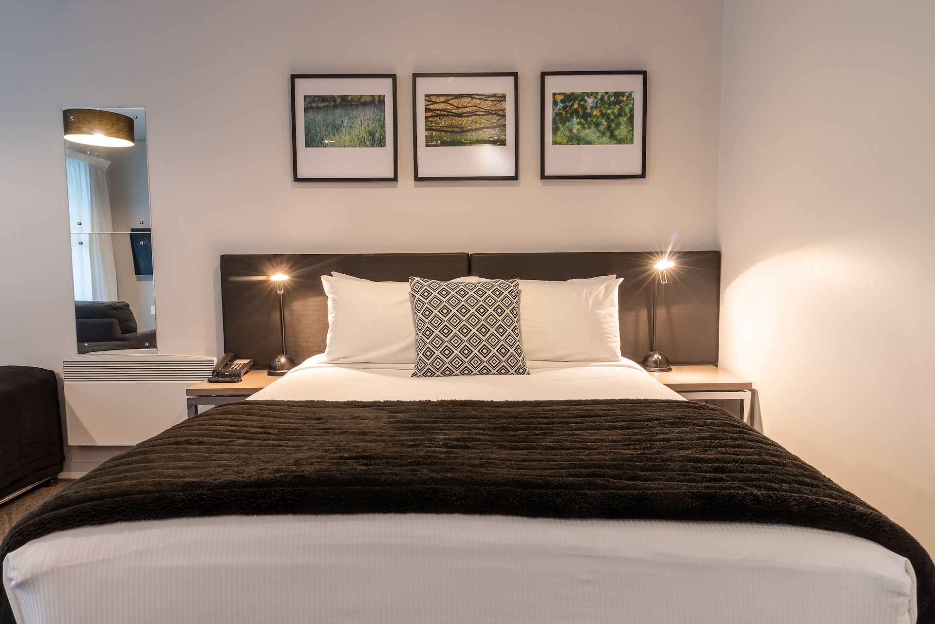 A hotel room with a king size bed and three pictures on the wall above it.