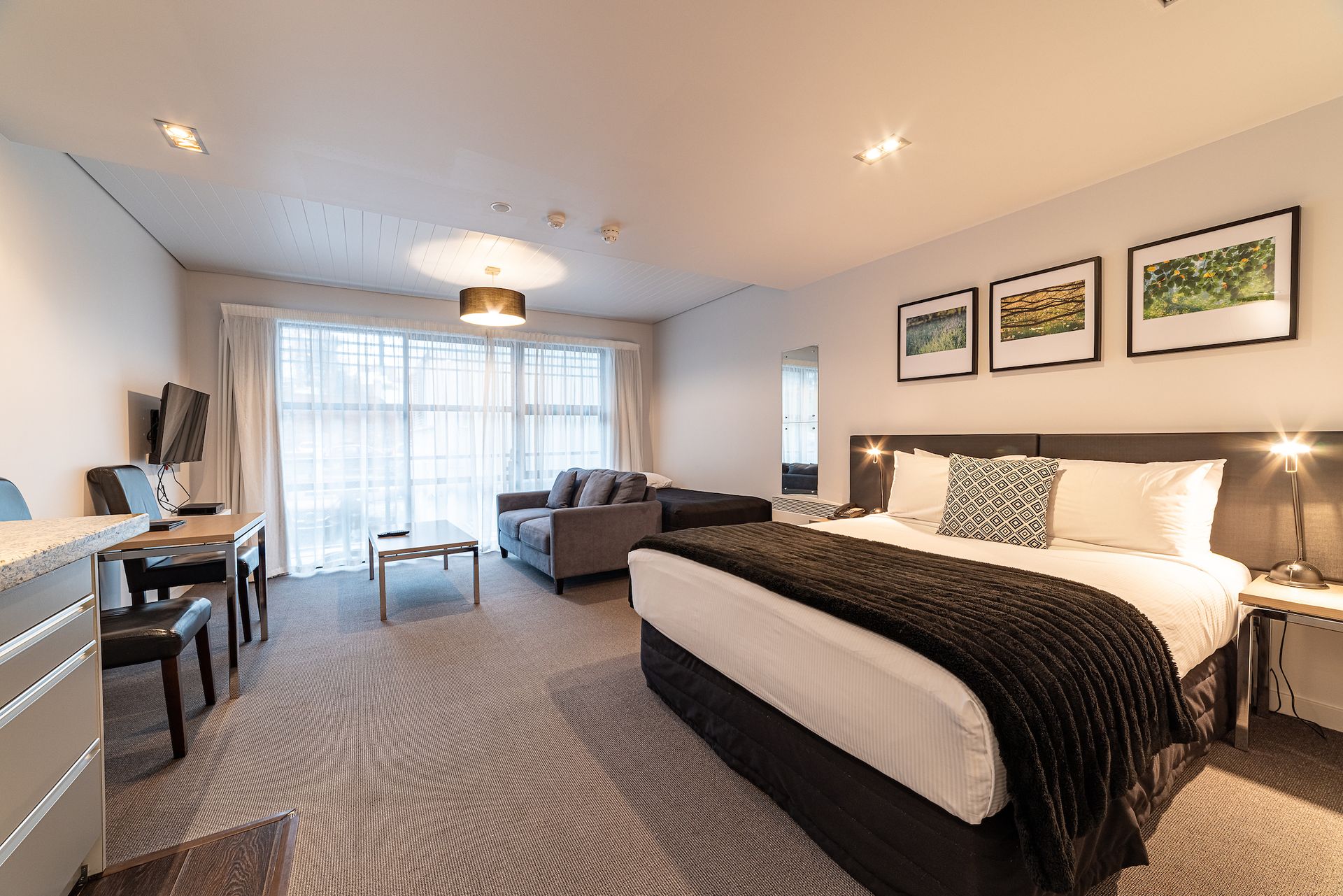 A hotel room with a king size bed , couch , desk and chairs.