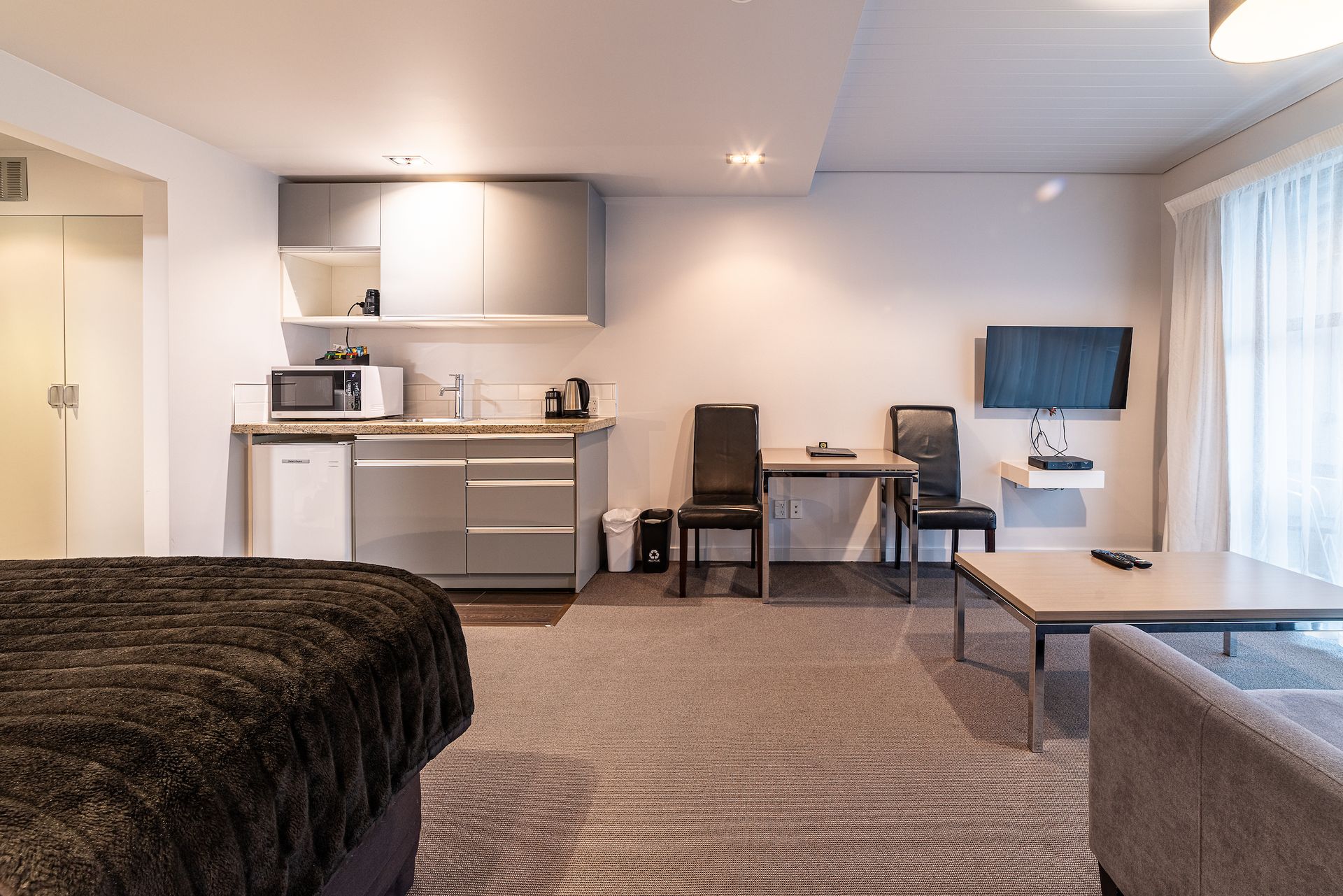 A hotel room with a bed , table , chairs , and television.