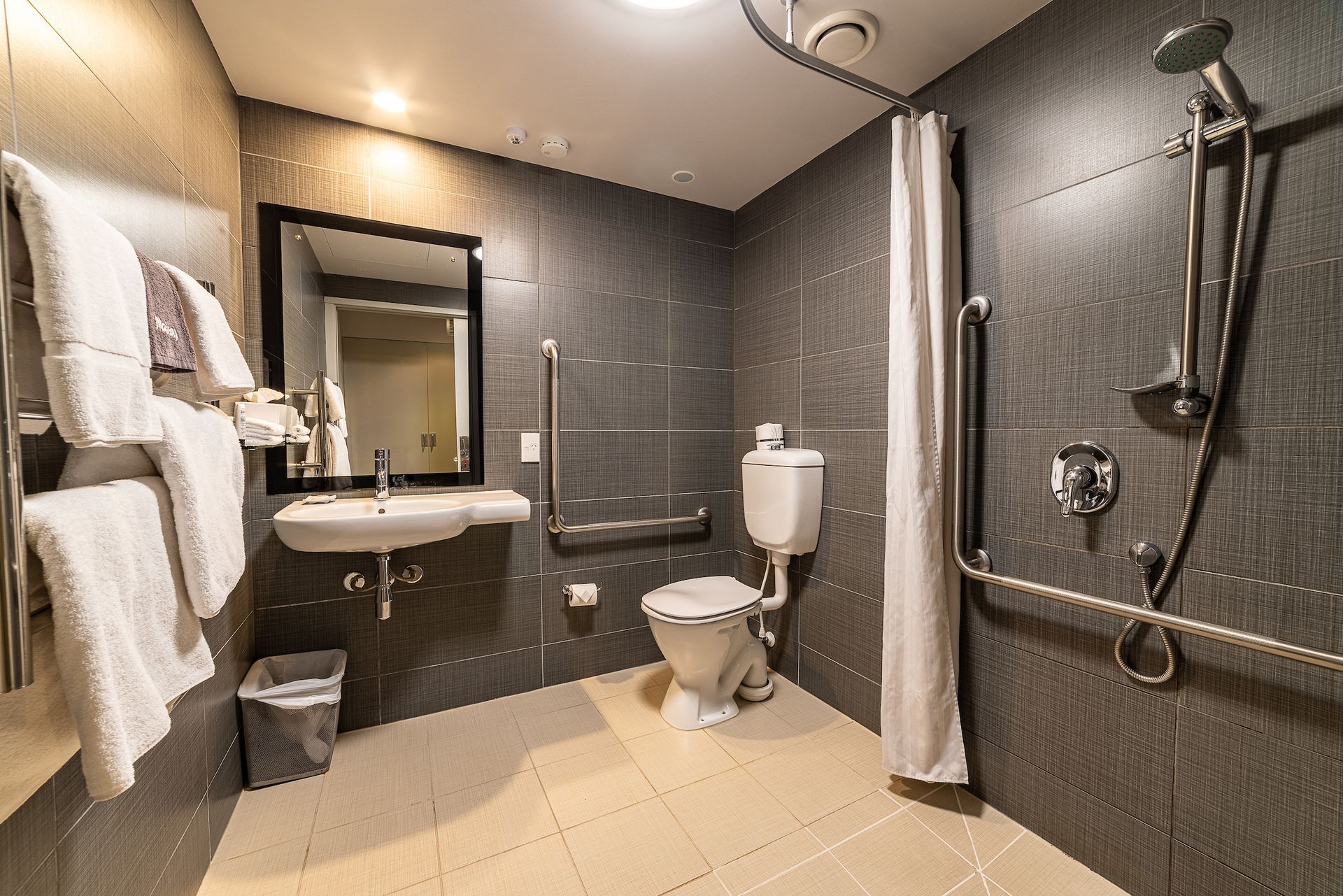 A handicapped bathroom with a toilet , sink and shower.