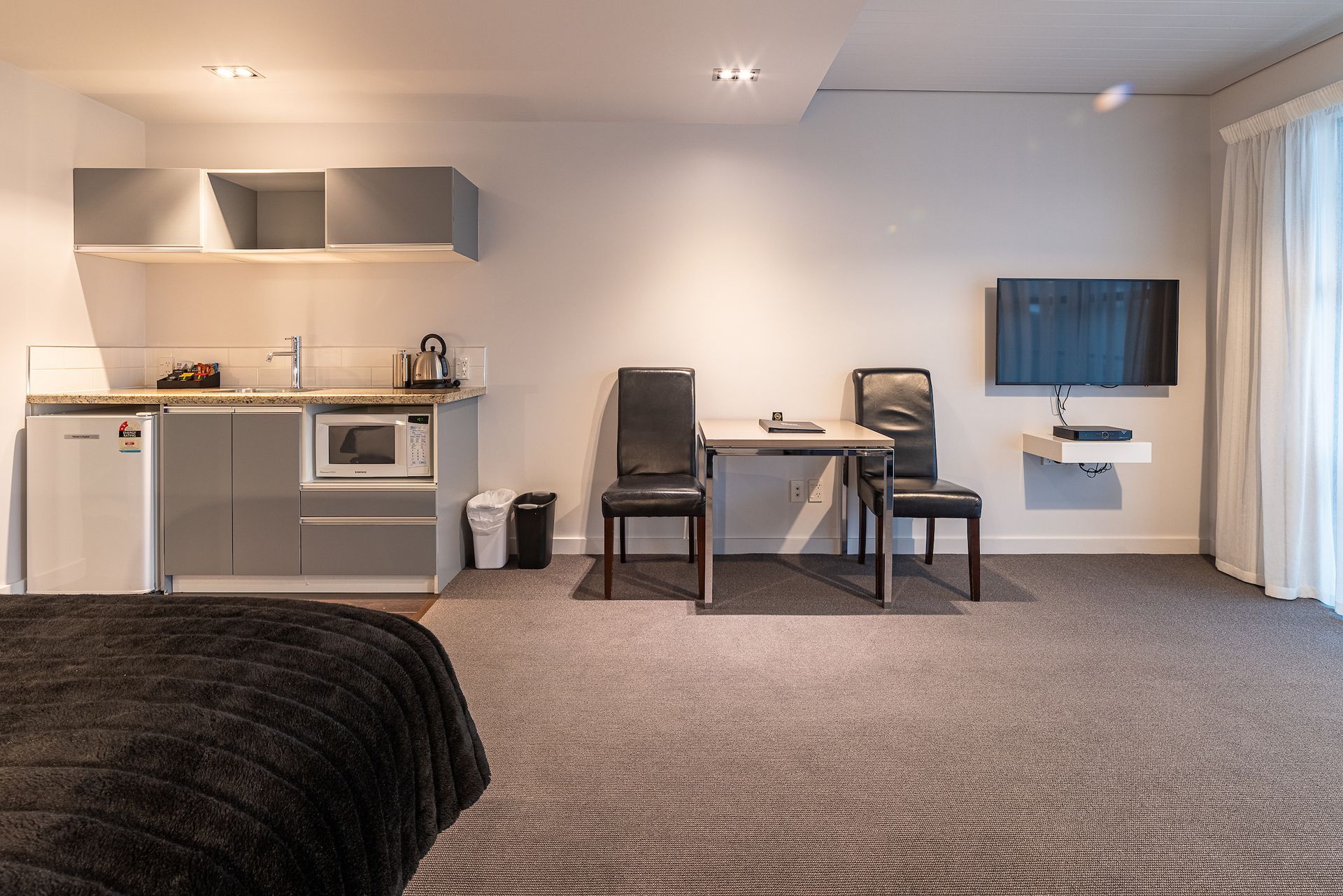 A hotel room with a bed , table , chairs and television.