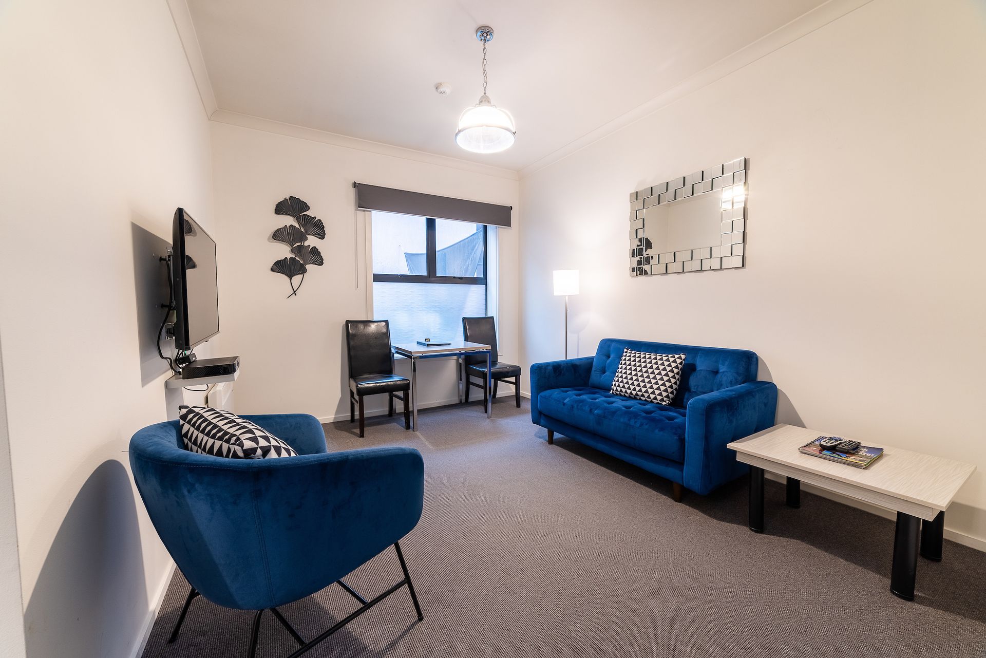 A living room with a blue couch and two blue chairs