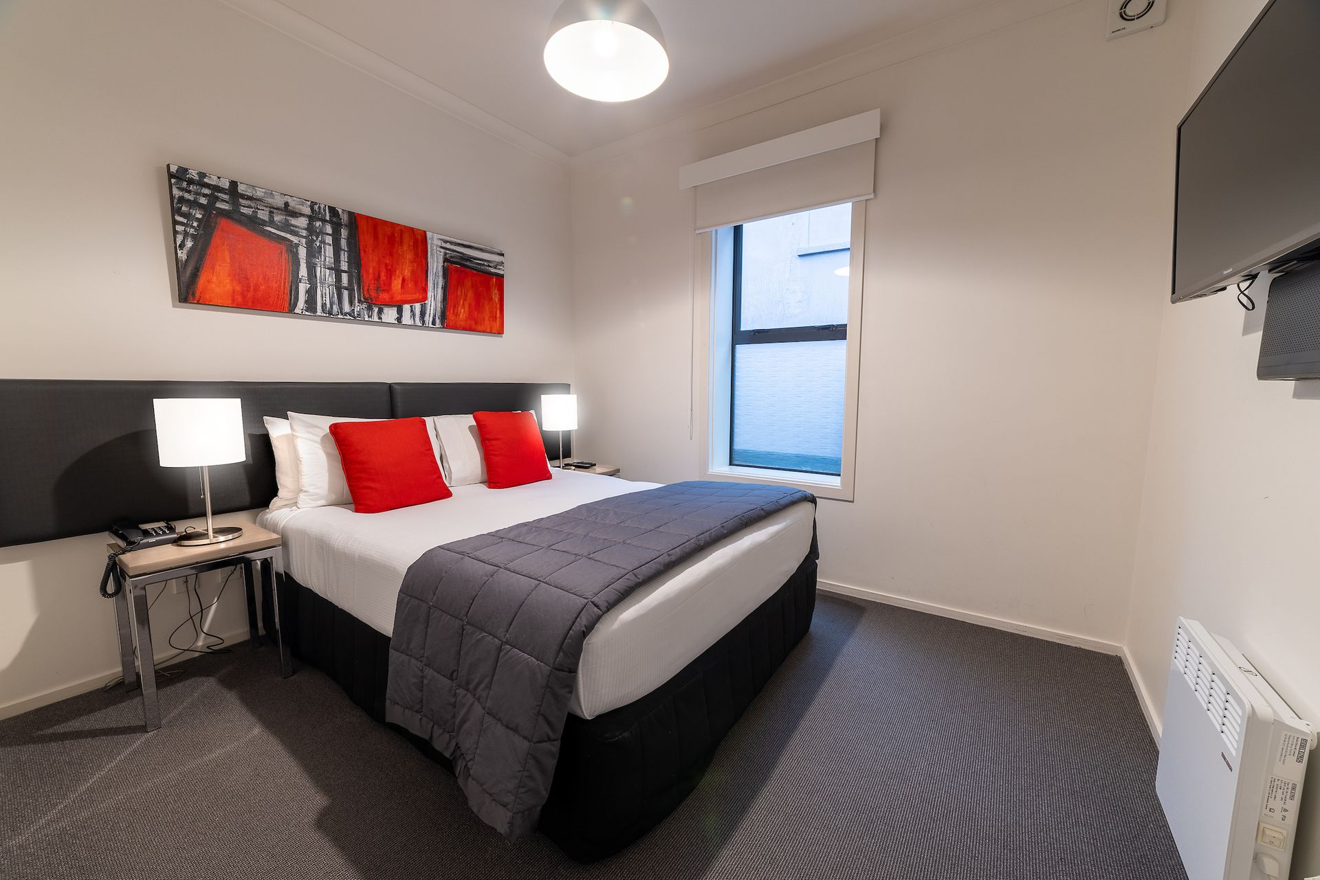 A hotel room with a king size bed and a television.