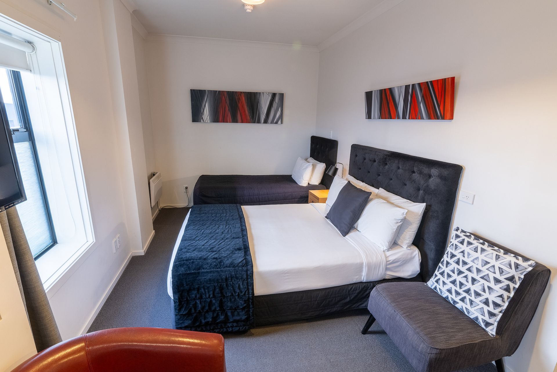 A hotel room with two beds , a chair , and a television.