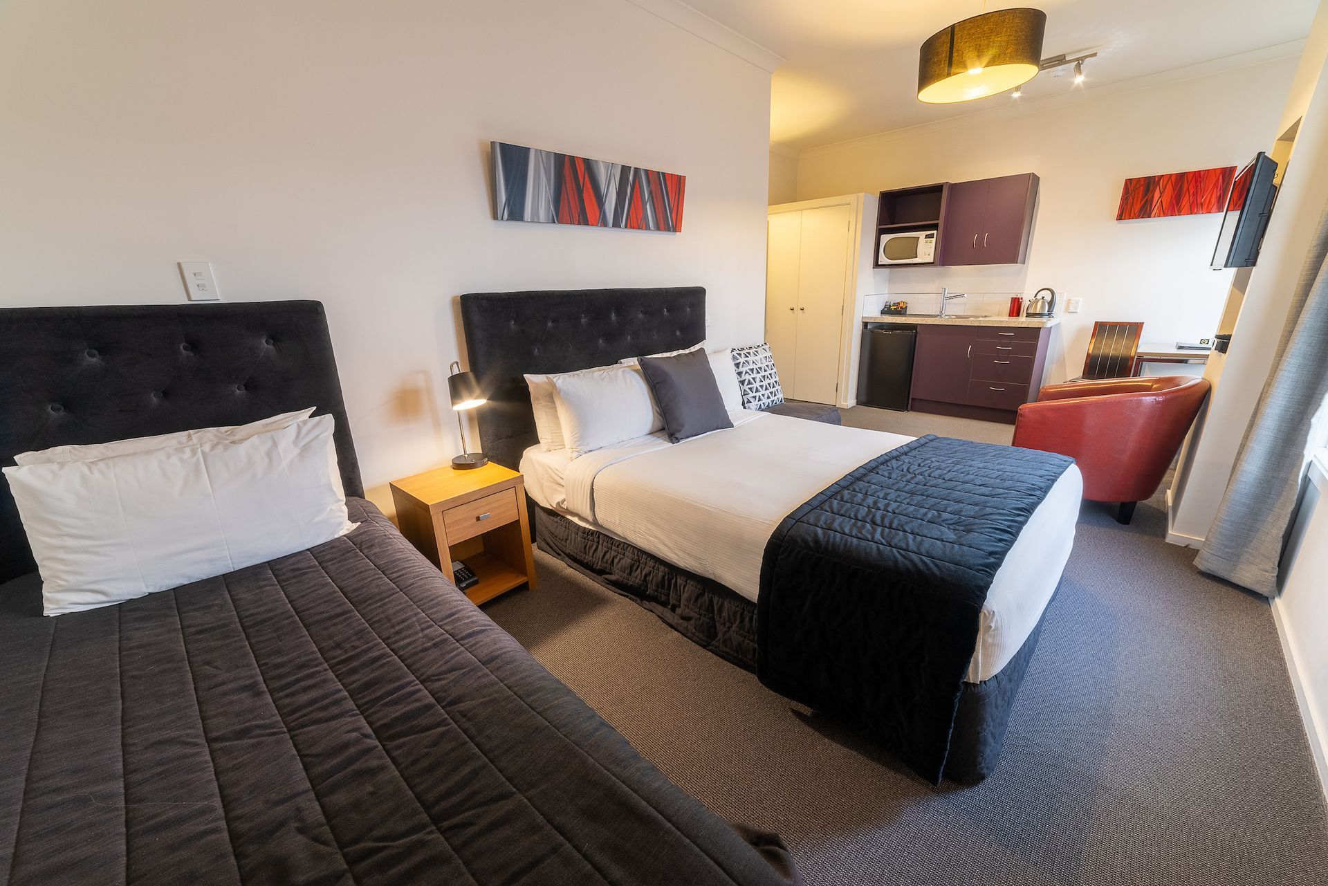 A hotel room with two beds and a kitchen.