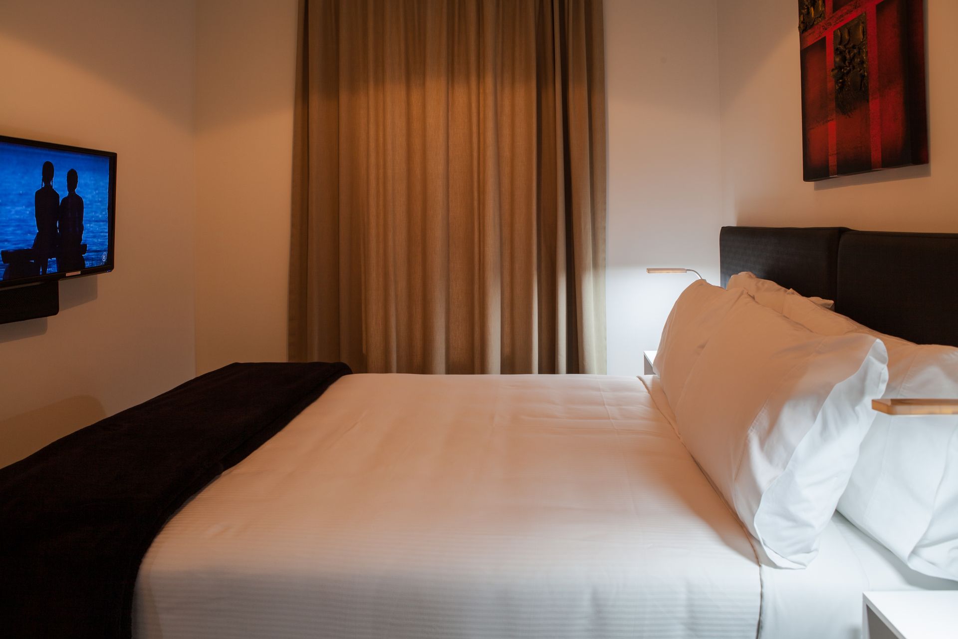 A hotel room with a bed , television , and window.