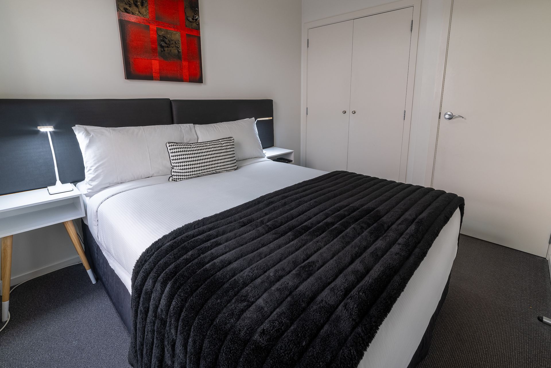A hotel room with a large bed and a painting on the wall.