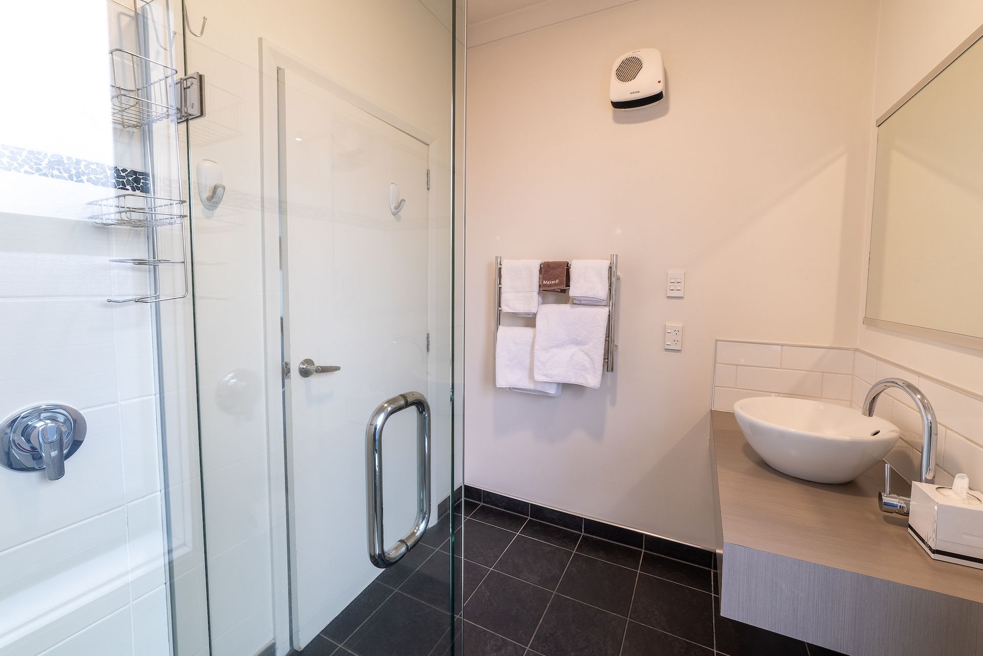 A bathroom with a sink , shower , and mirror.