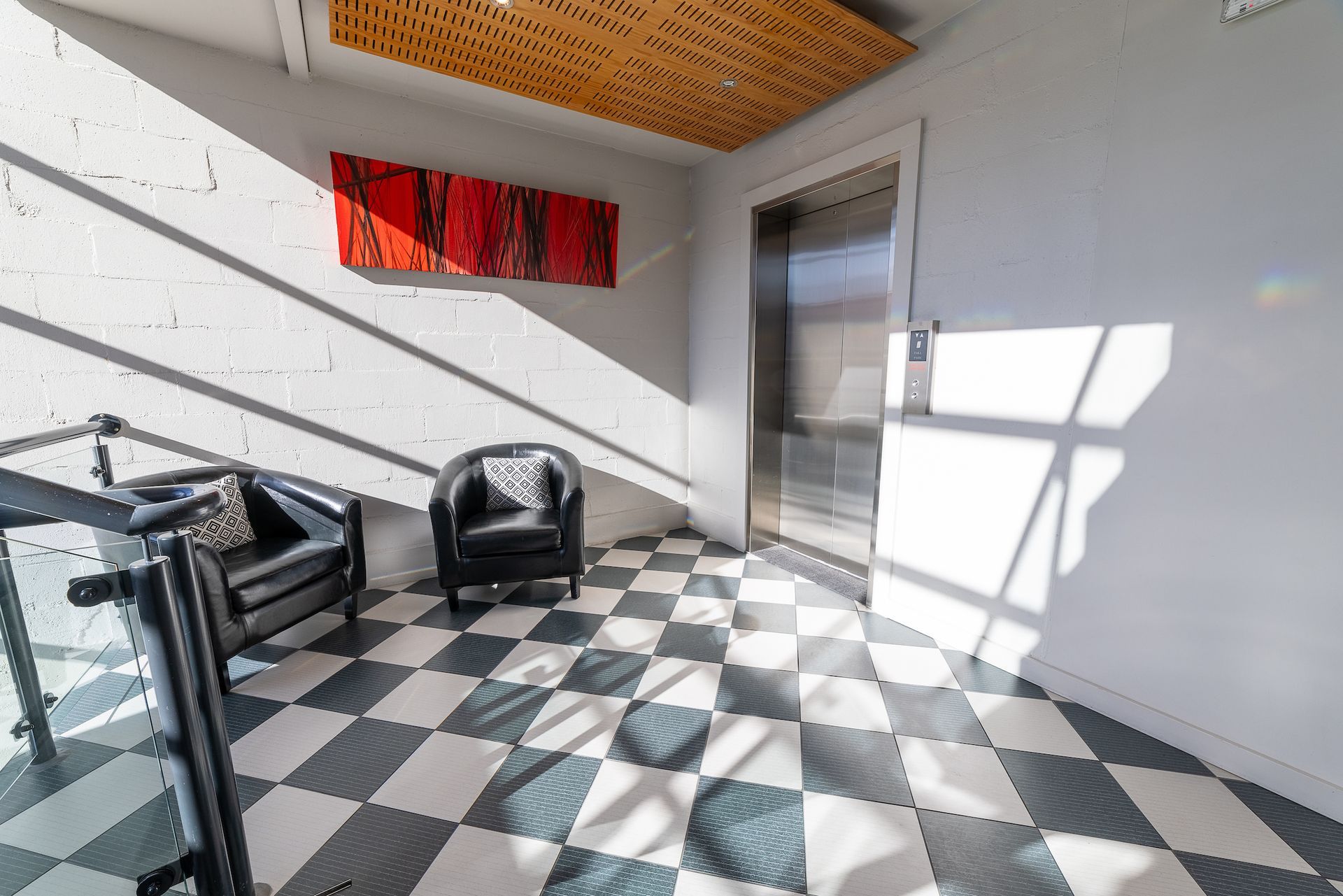 A hallway with a checkered floor and chairs