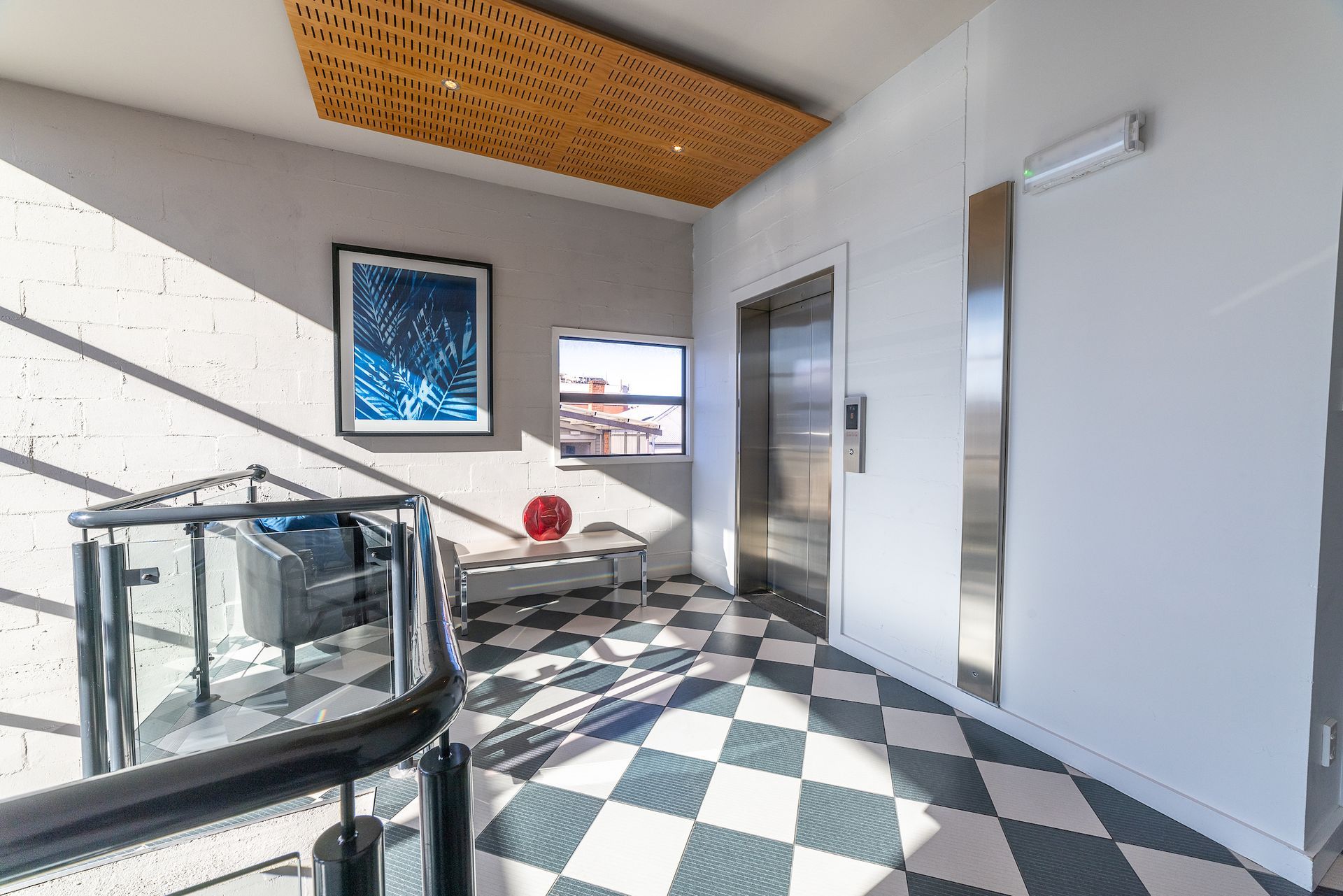 A hallway with a checkered floor and an elevator in a building.