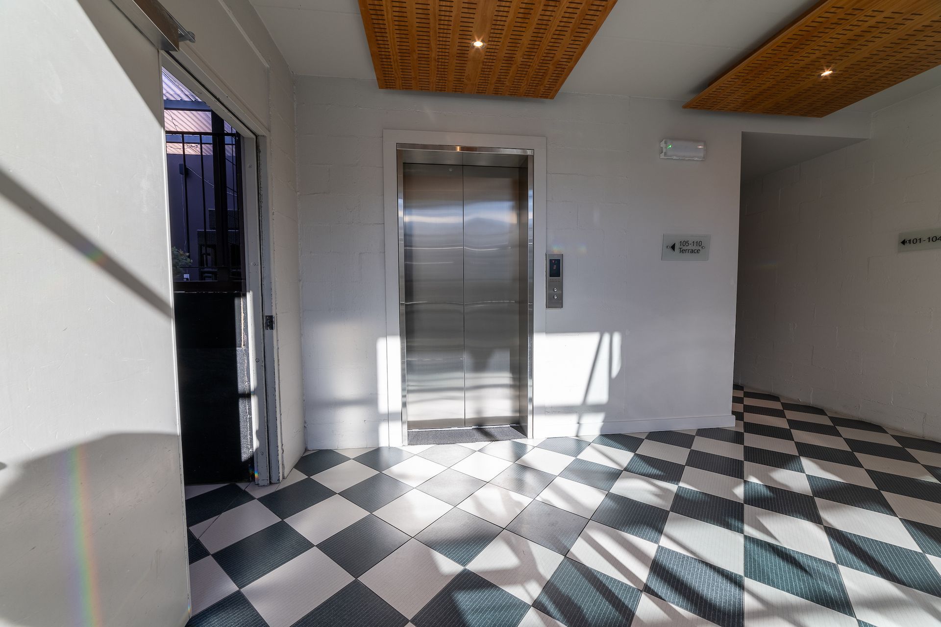 An elevator in a building with a checkered floor.