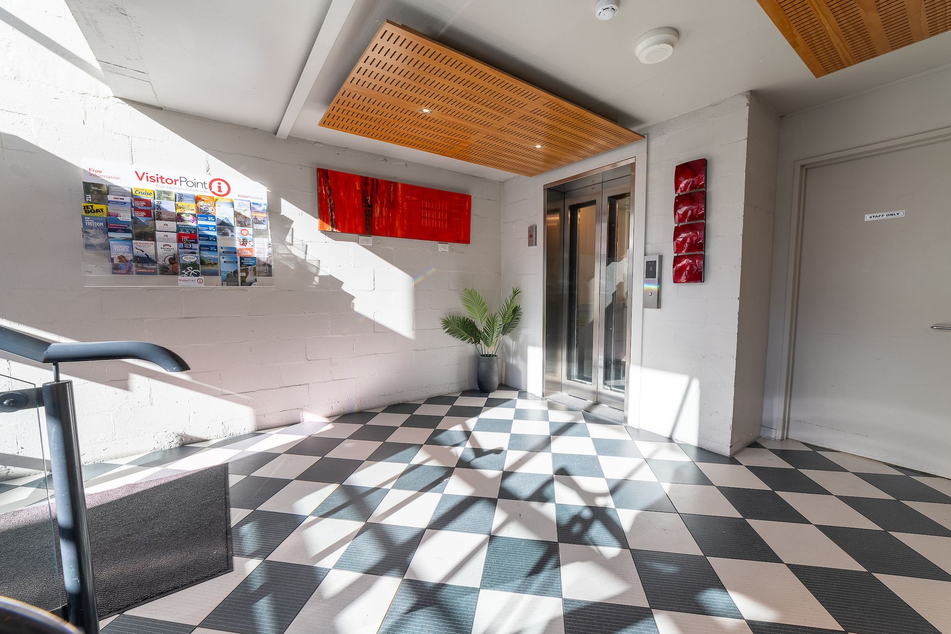A hallway with a checkered floor and an elevator.