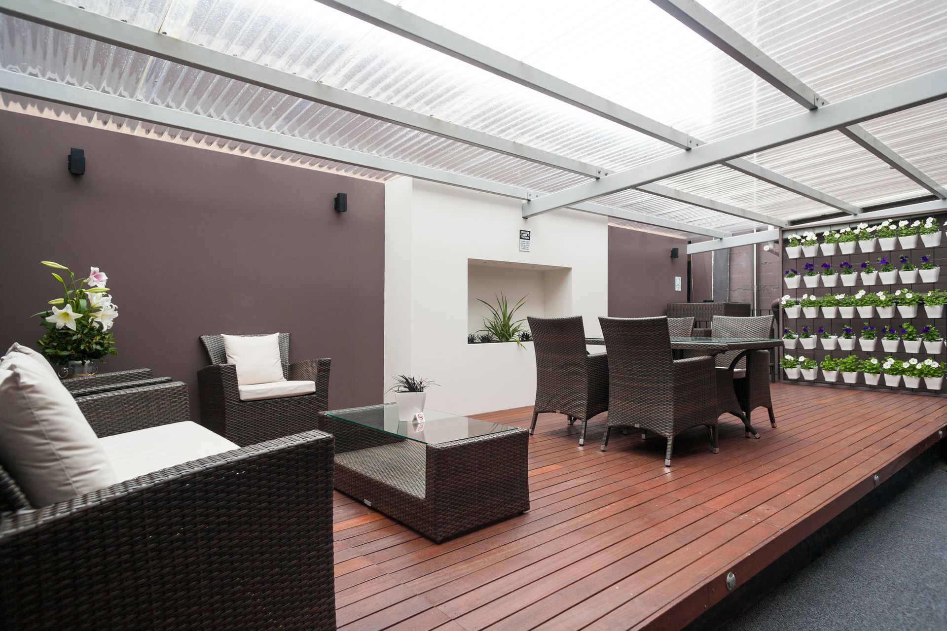 A patio with a table and chairs under a clear roof