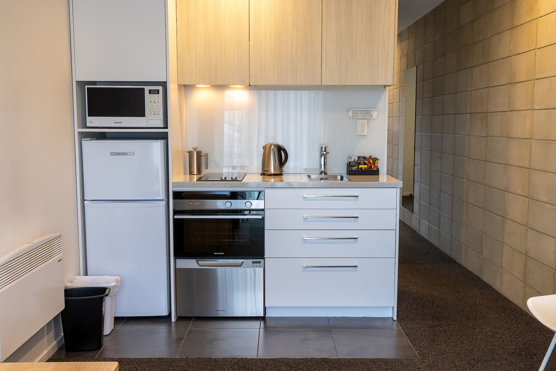 A small kitchen with a refrigerator , microwave , oven and sink.