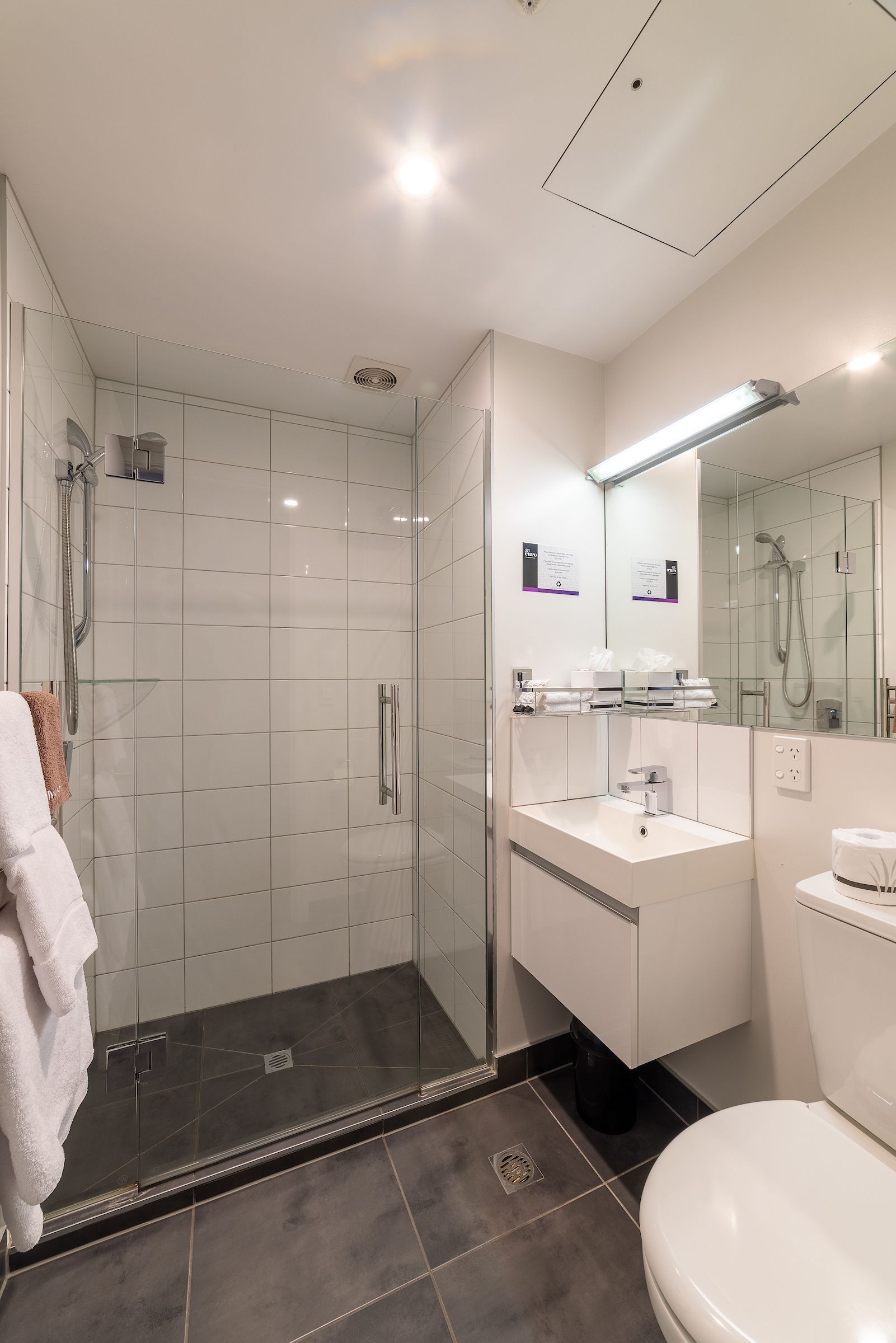 A bathroom with a toilet , sink and shower.