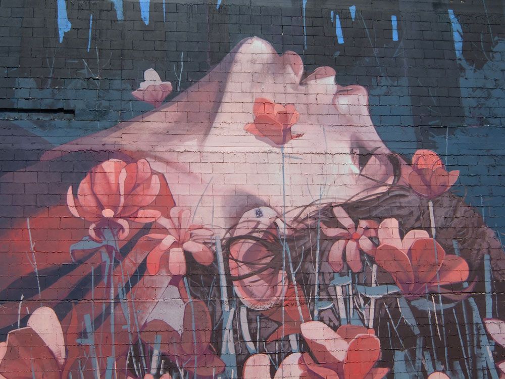 A mural of a woman surrounded by flowers on a brick wall.