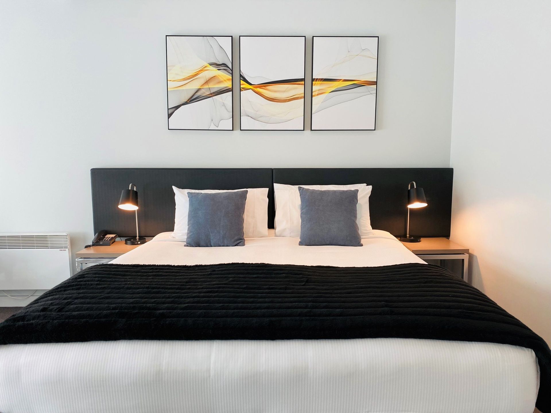 A hotel room with a bed and three paintings on the wall