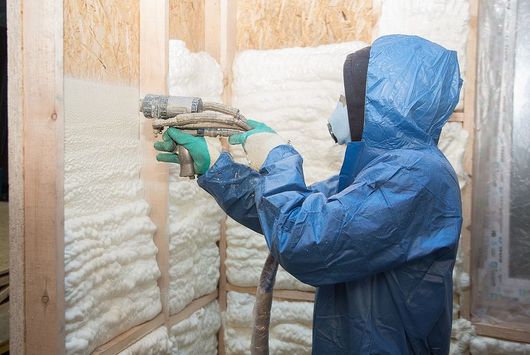 a man in a blue coverall spray painting a wall