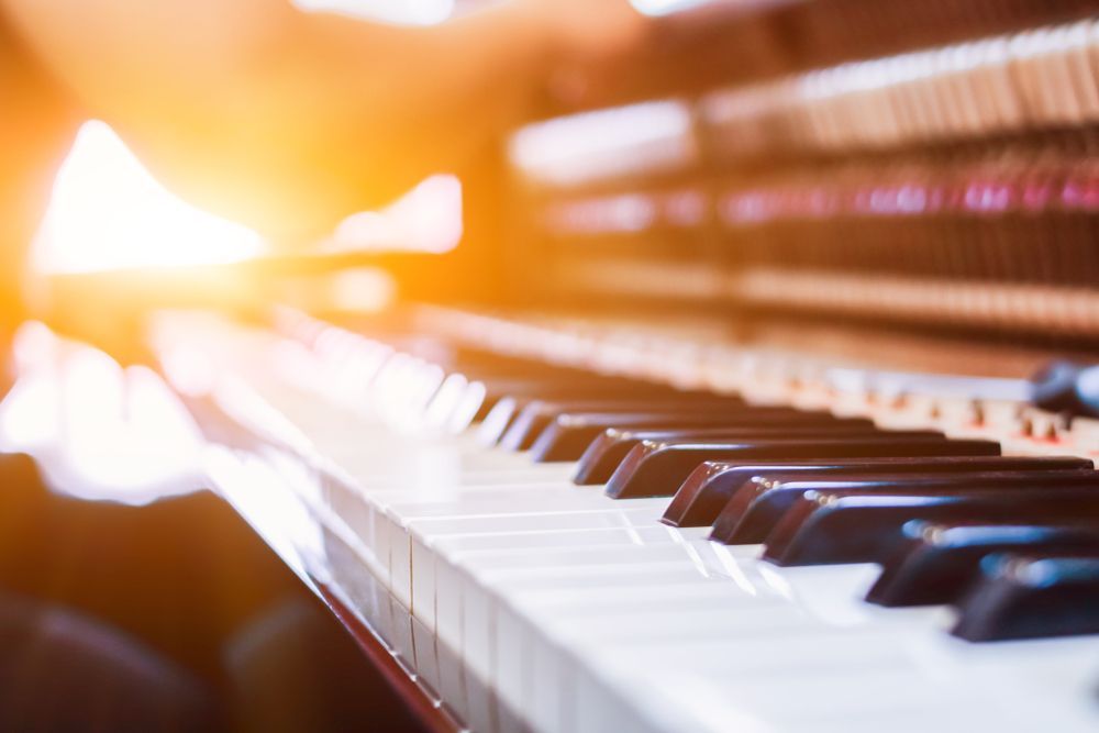 A close up of a piano keyboard with the sun shining through the keys.