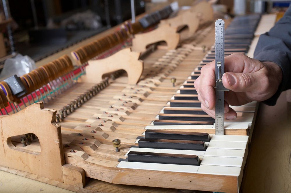 A person is measuring a piano keyboard with a ruler.