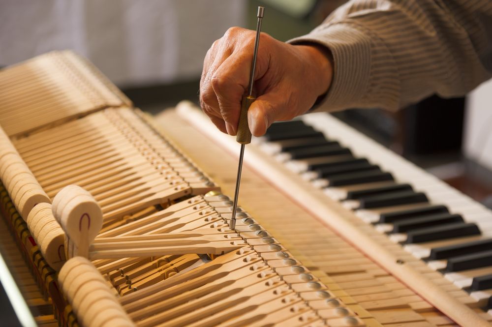 A person is working on a piano with a screwdriver.