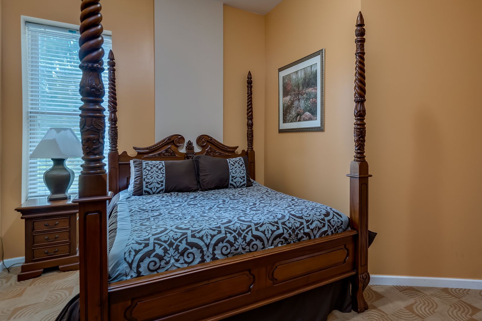 A bedroom with a four poster bed and a lamp
