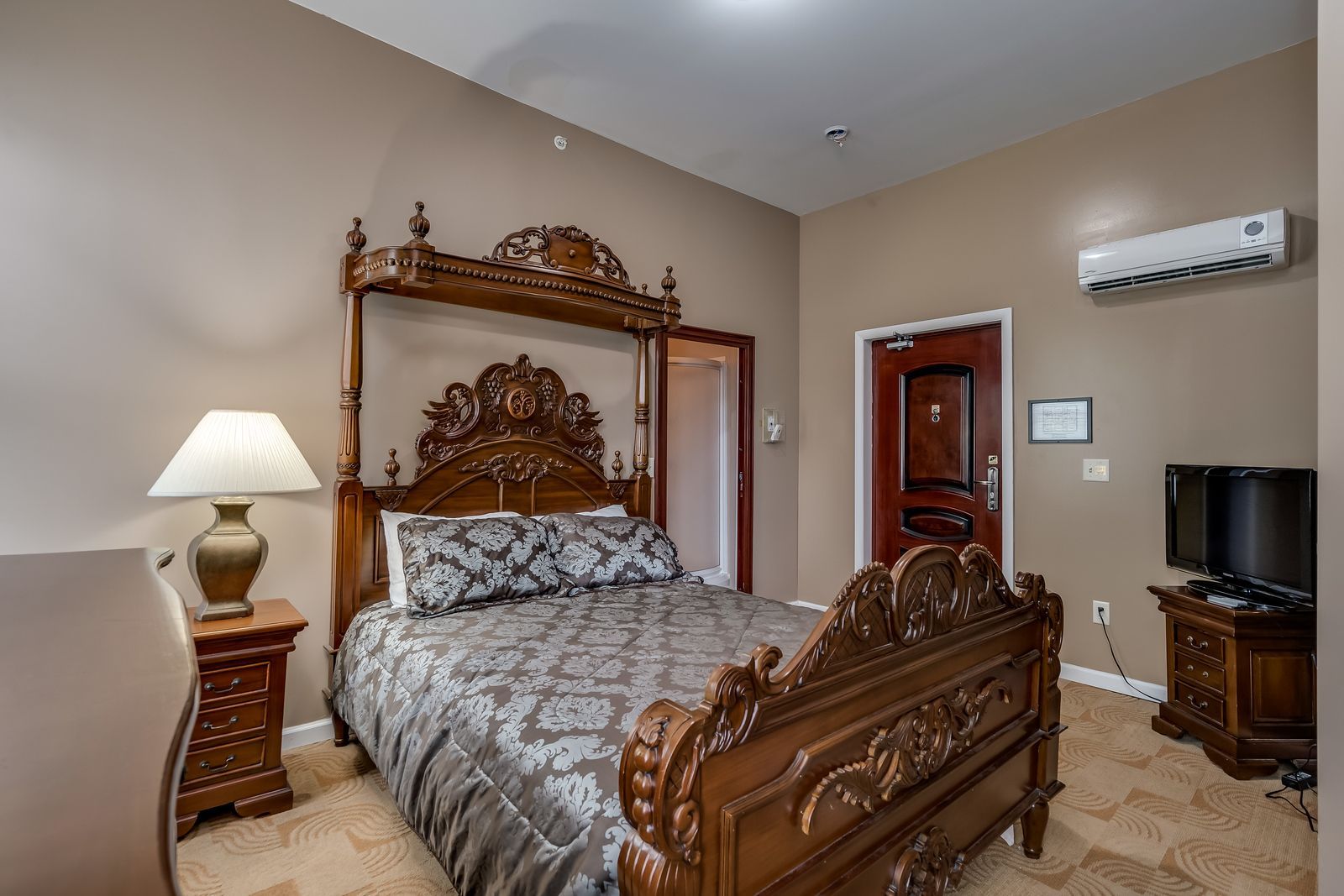 A bedroom with a king size bed , nightstand , lamp and television.