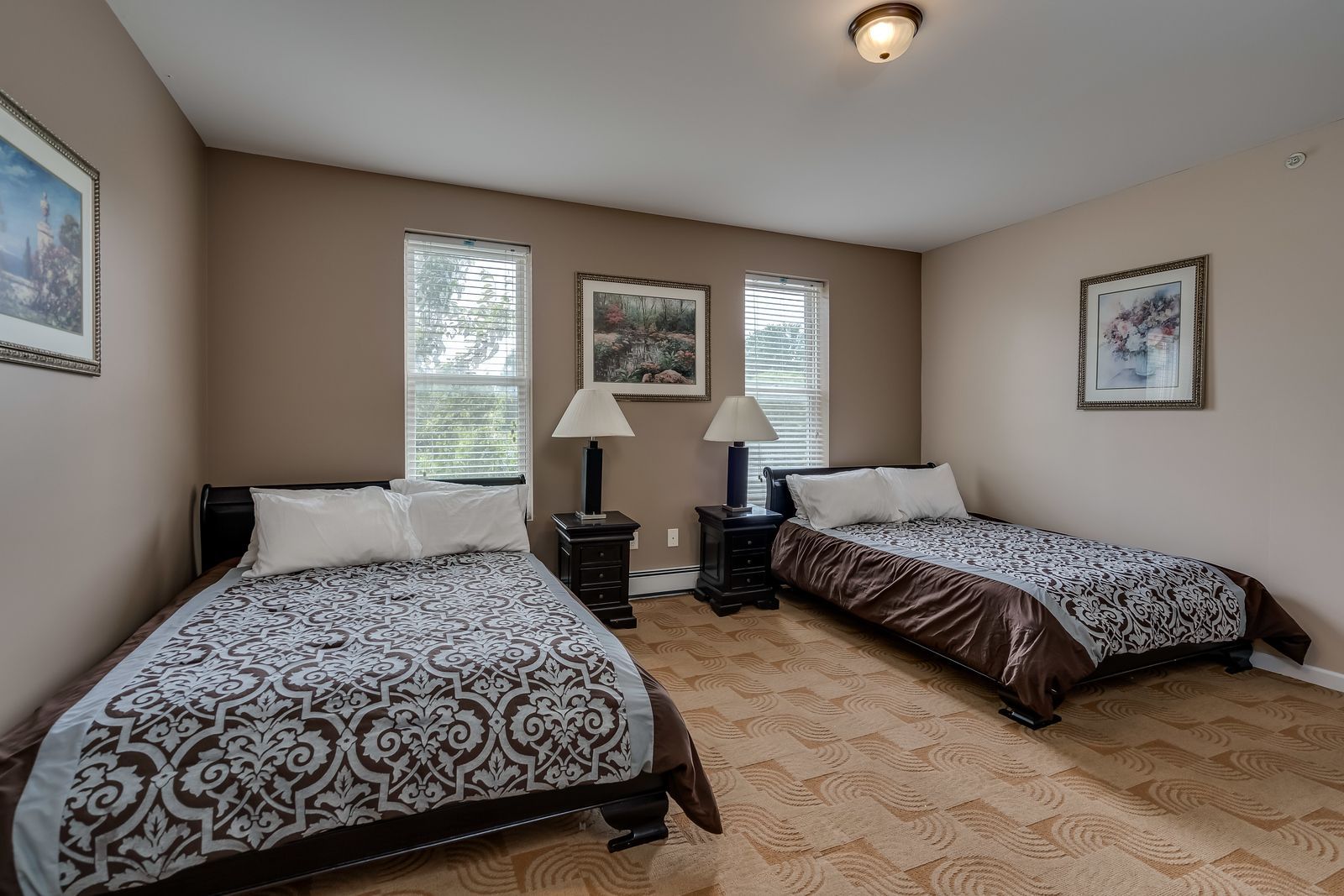 A bedroom with two beds and two lamps