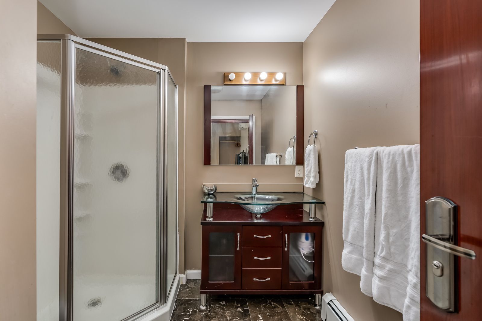 A bathroom with a sink , mirror and shower stall.