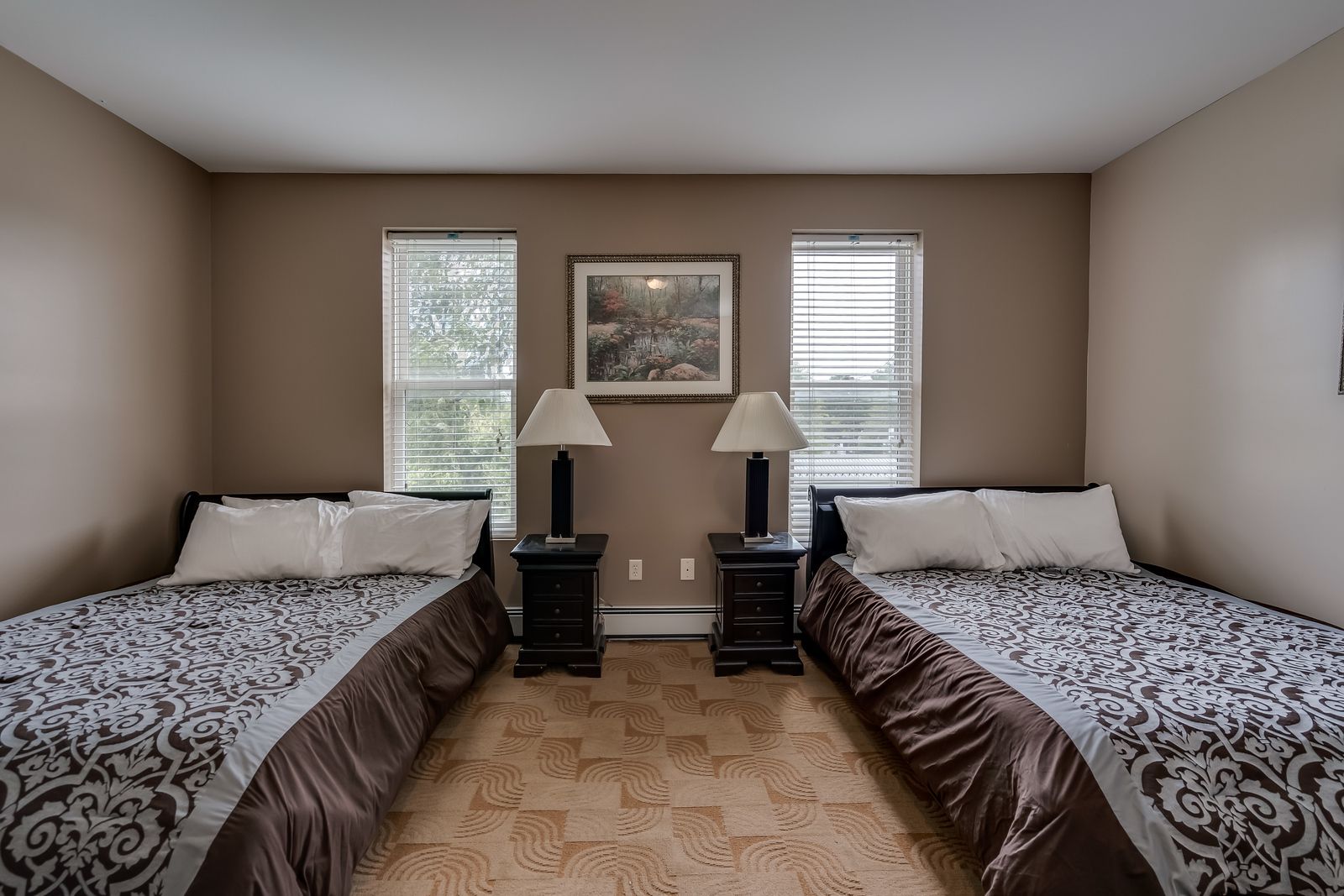 A bedroom with two beds and two lamps
