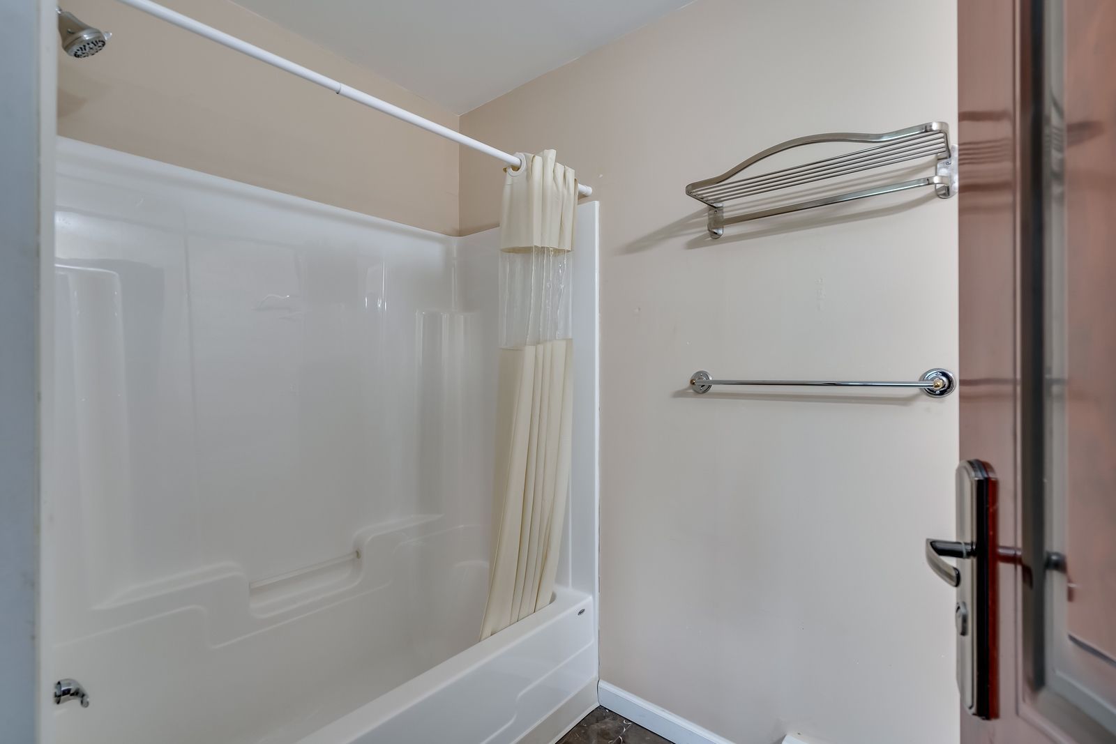 A bathroom with a tub , shower , and towel racks.